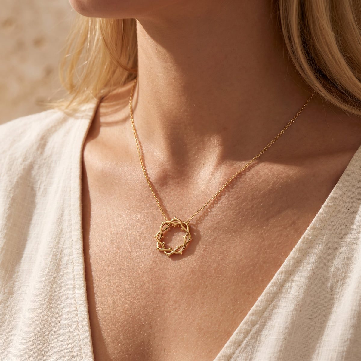 Close-up view of the gold crown of thorns necklace worn on a model in a v-neck top.