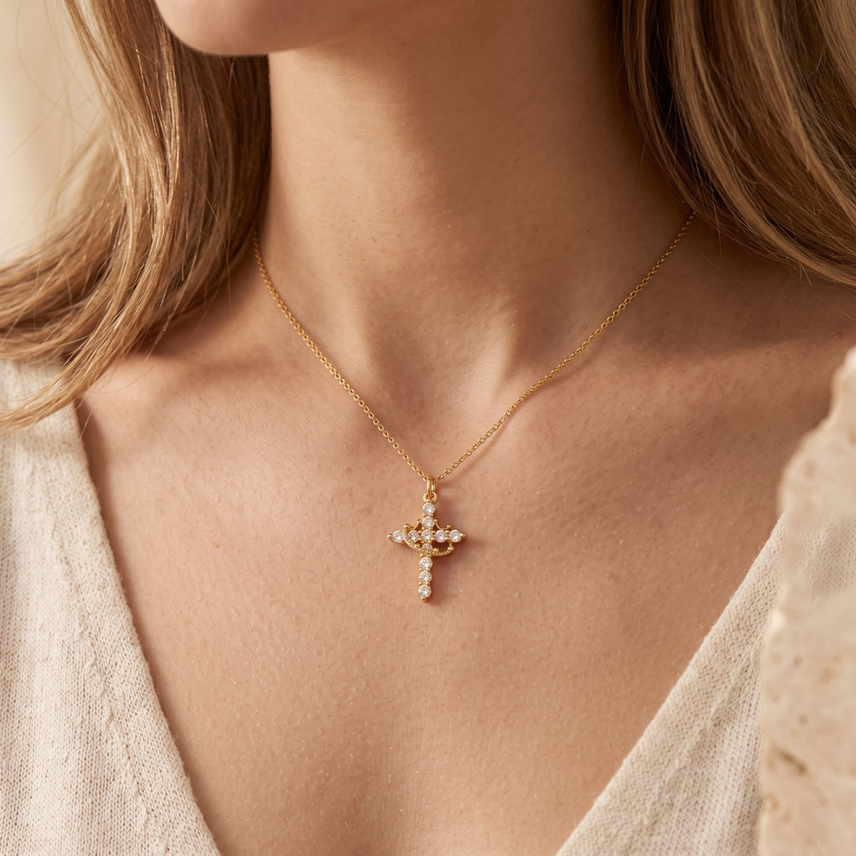 Model wearing the gold-tone crown cross pendant necklace, shown in a wider front portrait view.
