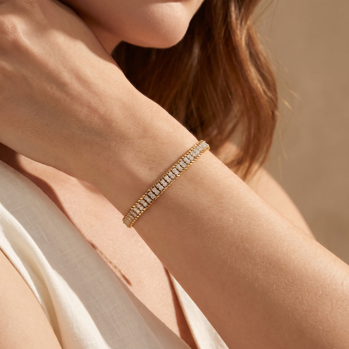 Person wearing the gold-tone double-row pavé link bracelet on a wrist in a warm lifestyle view.