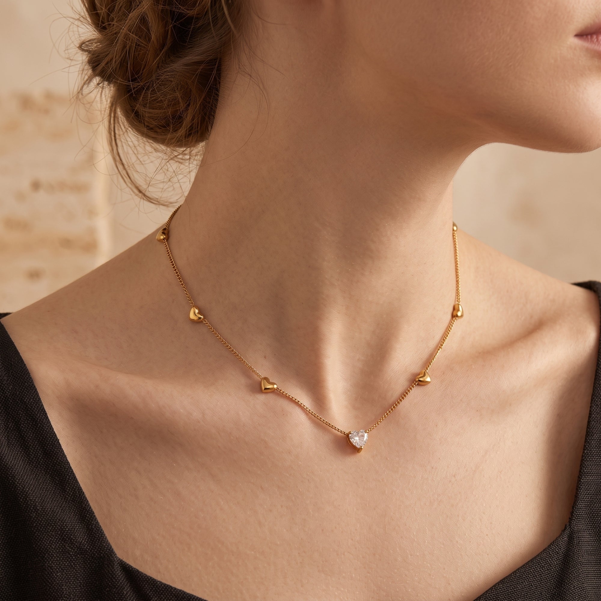 18K gold Amoris heart necklace with a heart-cut simulated diamond worn by a model in a black dress.