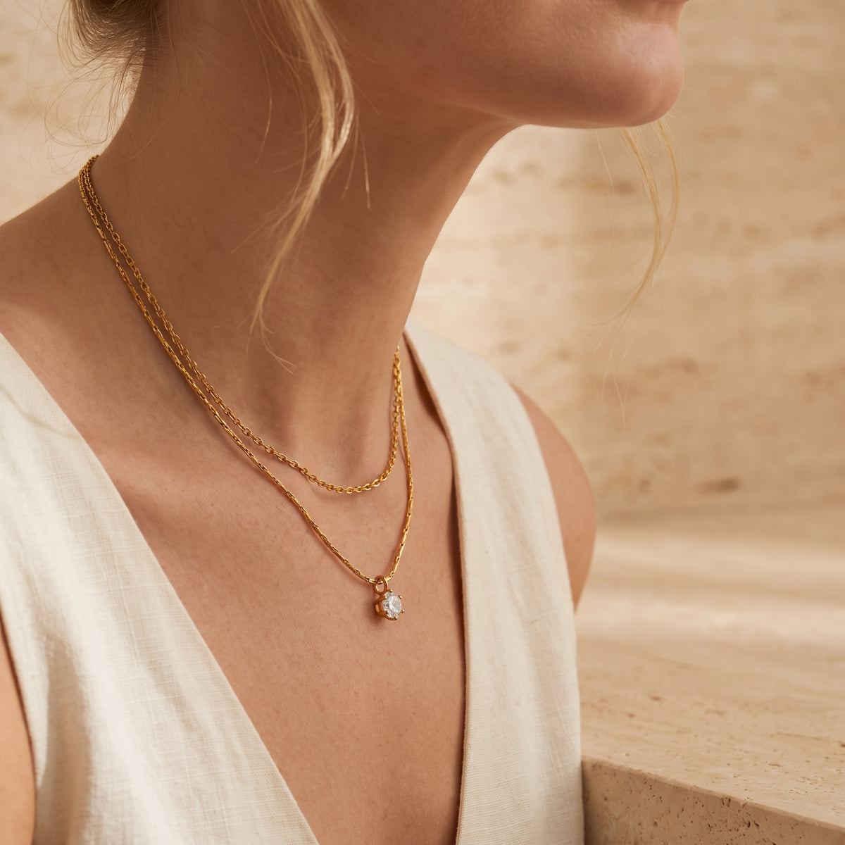 Side-angle view of a model wearing the gold-tone double-strand necklace with a round pendant.