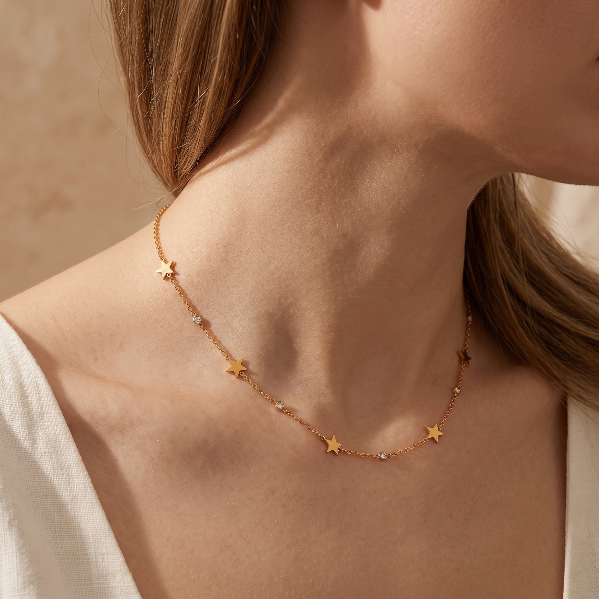 Side view of the gold Astrasienne star charm necklace with diamond bezels on a model.