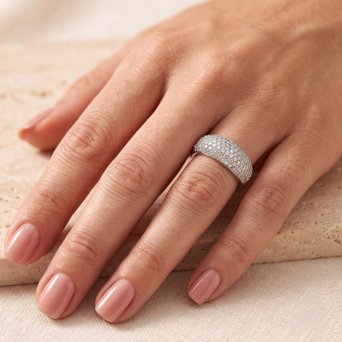 Wide solid white gold dome ring with pave-set cubic zirconia on a finger for scale and fit.