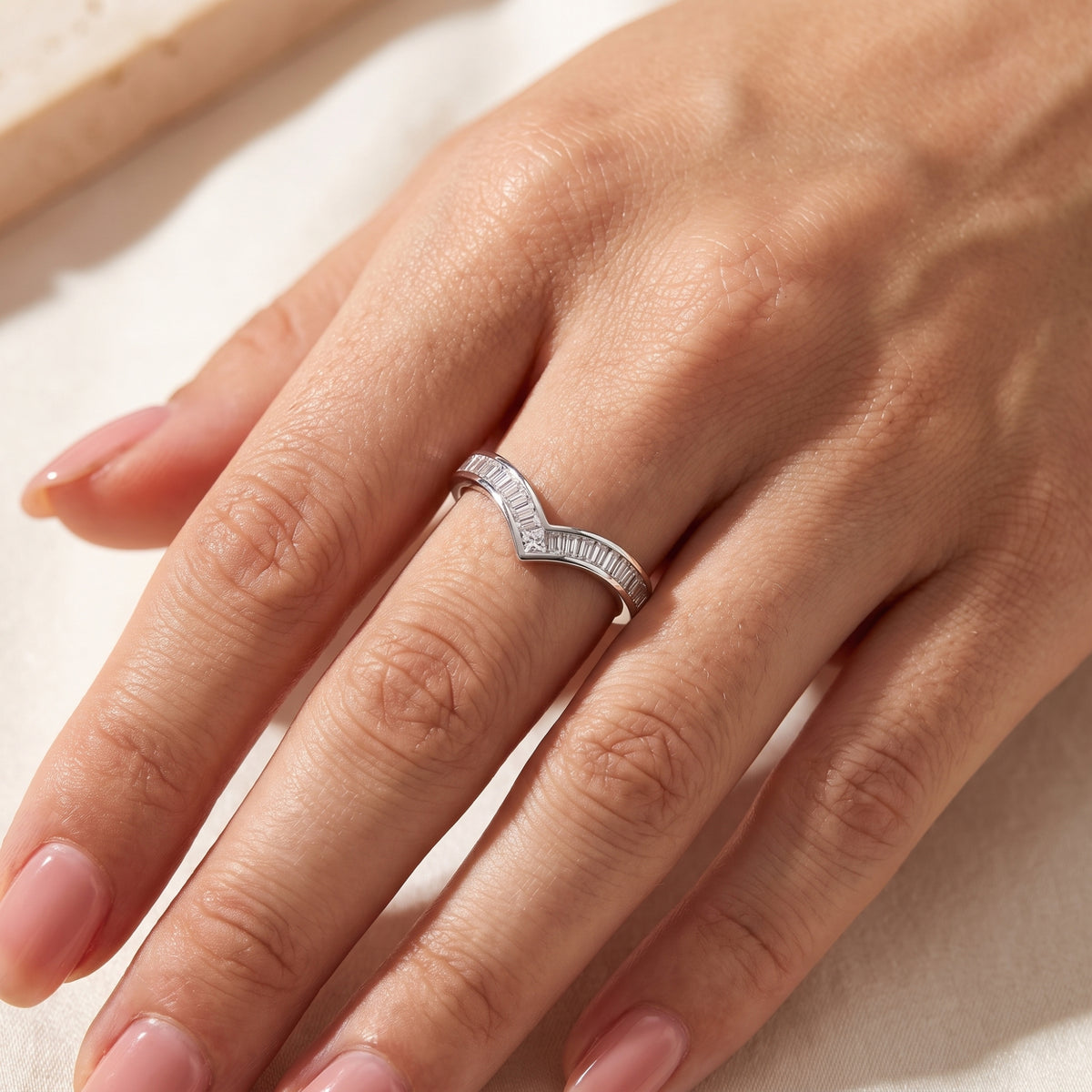 Silver baguette chevron ring worn on a hand, with the V-shaped point facing toward the fingertip.