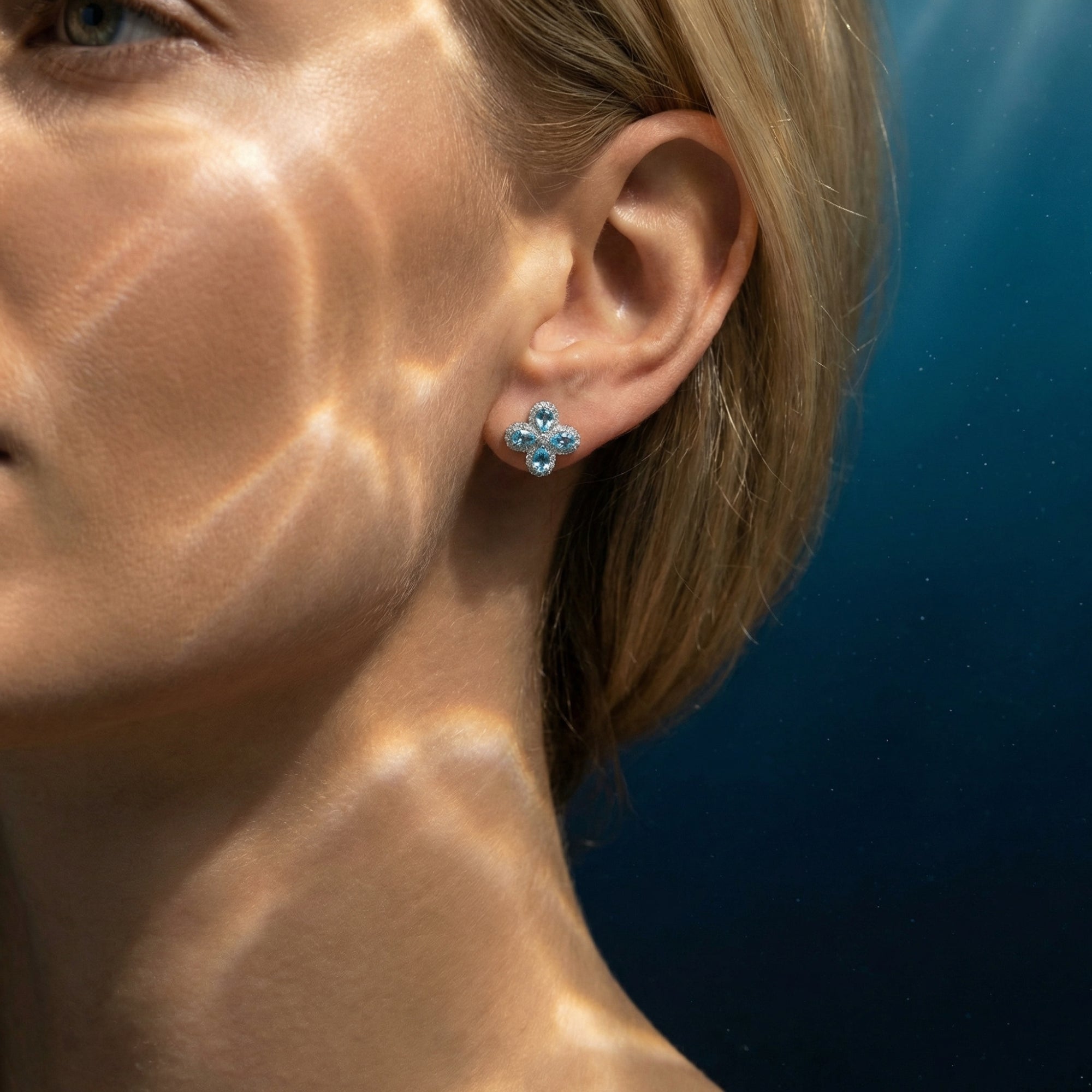 Side view of a model wearing the silver floret aquamarine cluster earrings with shimmering light reflections.