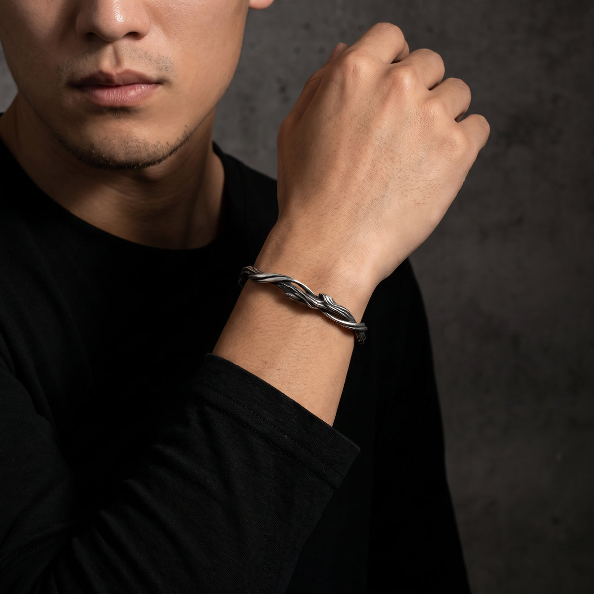 Close-up of a man wearing the silver twisted vine cuff bracelet on his raised wrist.