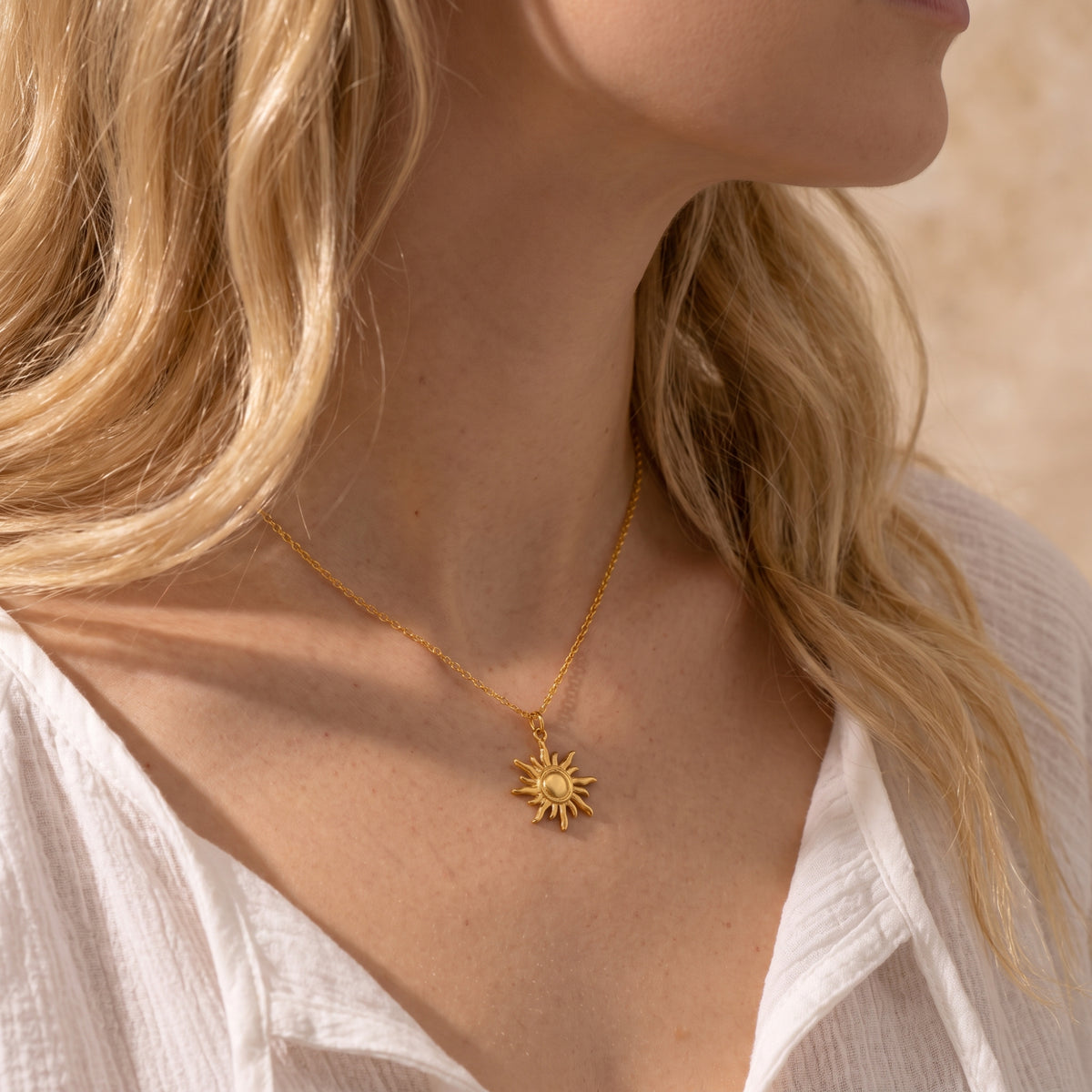 Side-profile view of a blonde woman wearing the gold sunburst pendant necklace.