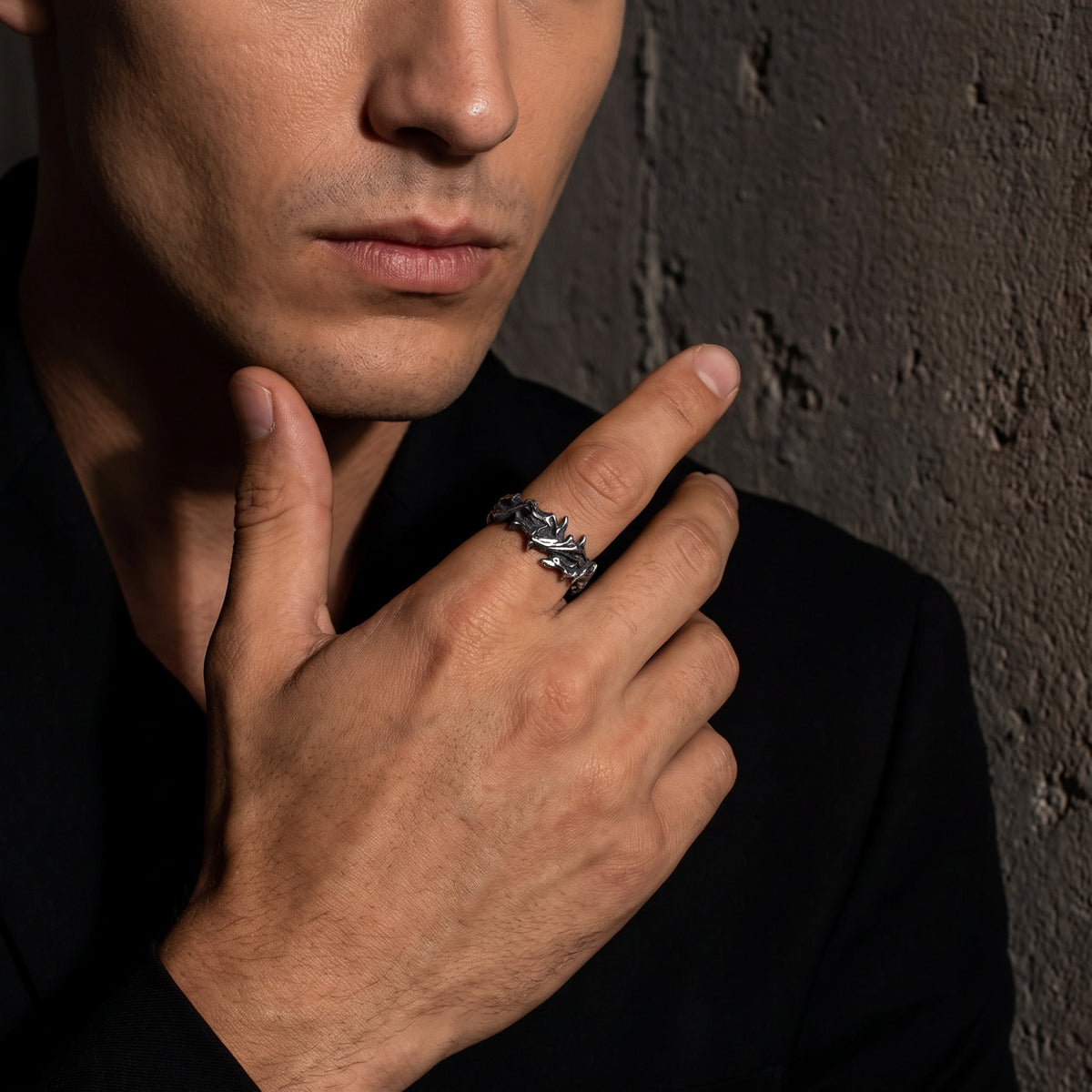 Close view of a model wearing the oxidized silver thorn open band ring with a hand near the chin.