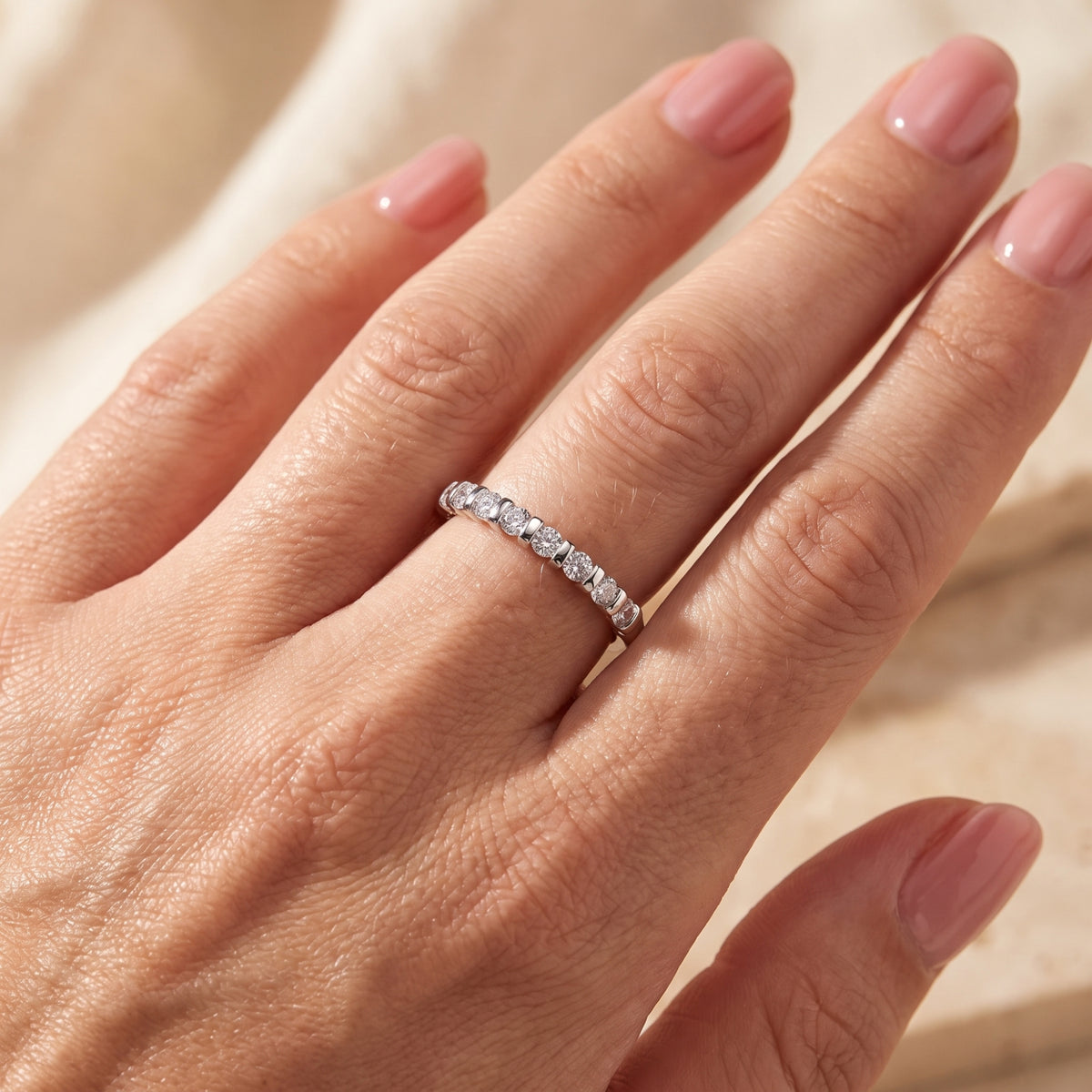 Close-up of a silver bar-set ring worn on a hand with soft pink manicured nails.