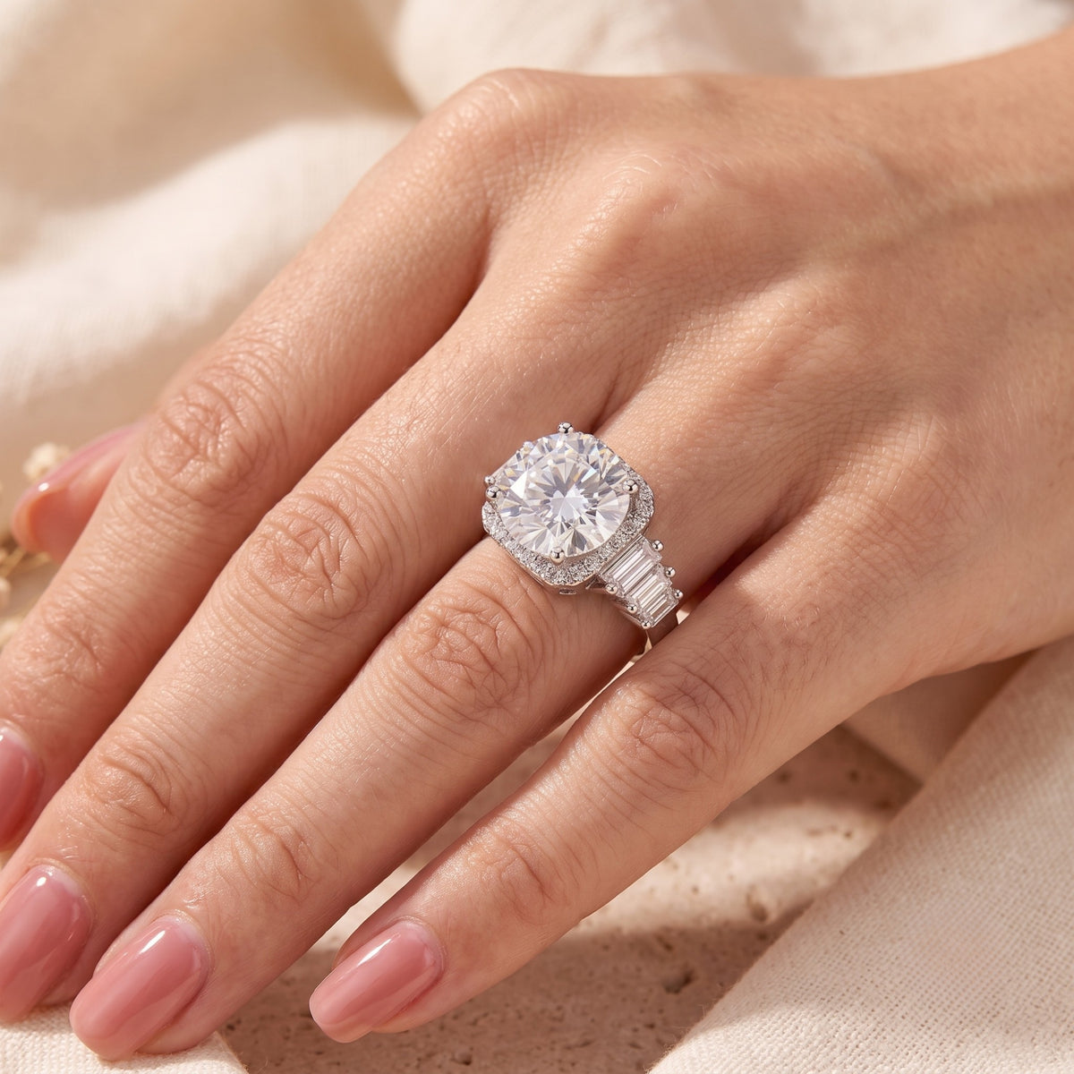 Close-up on-hand view of the silver halo ring, highlighting the round center stone, halo, and side baguettes.