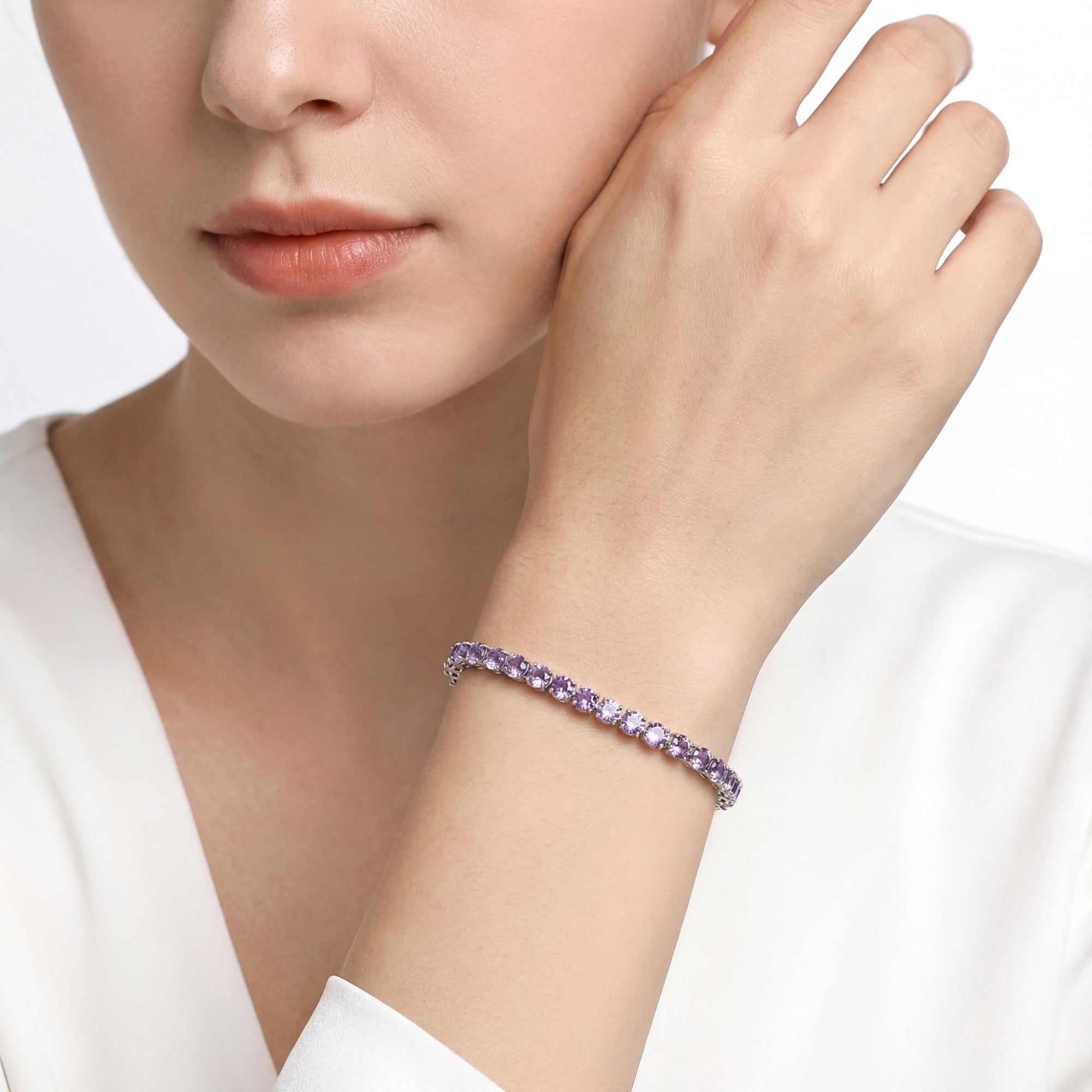 Stainless steel tennis bracelet with round purple simulated amethysts worn on a woman's wrist.