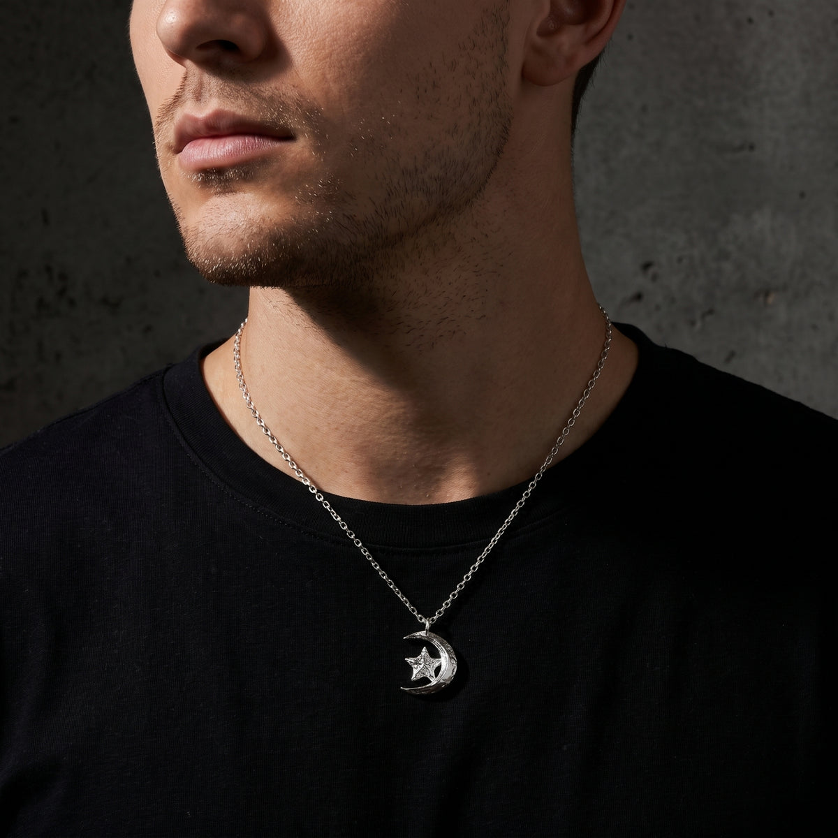 Close-up of a man wearing the silver crescent moon and star pendant over a black T-shirt.