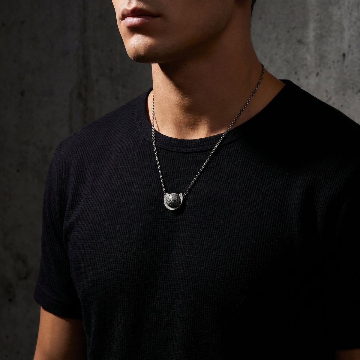 Male model wearing the silver orbital lunar pendant necklace against a black t-shirt.