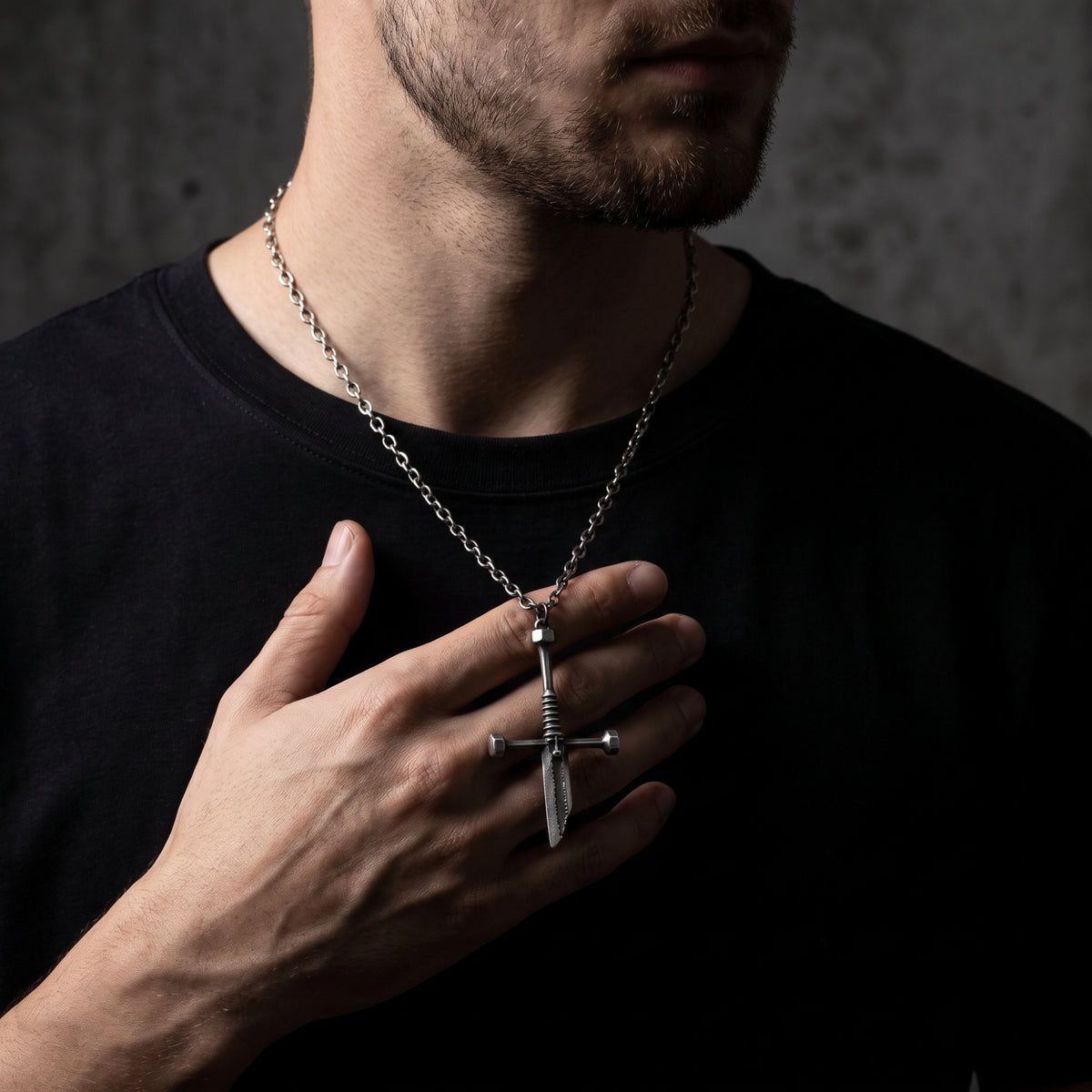 Close-up of a bearded man wearing the silver dagger pendant while holding it against his chest.