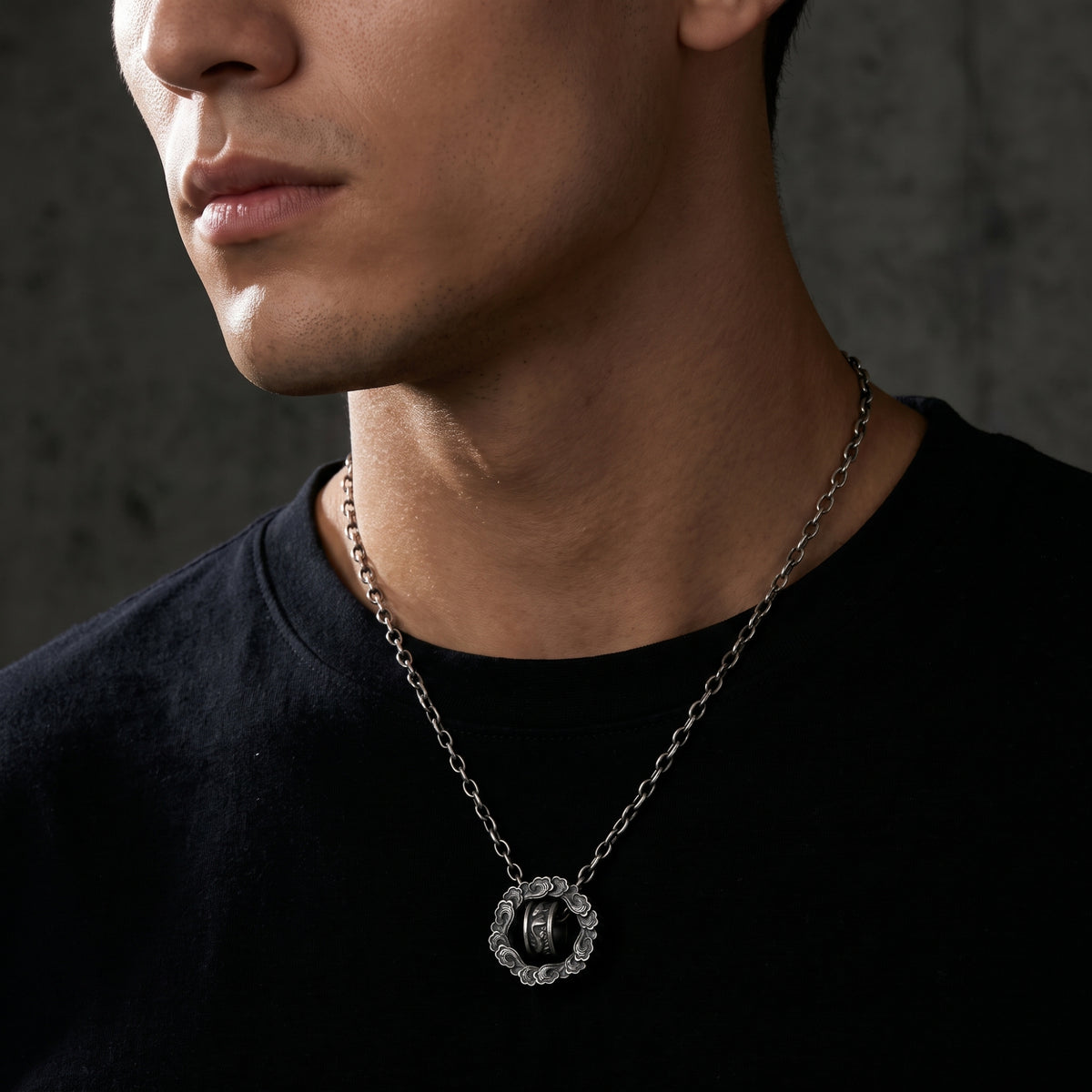 Close-up of a model wearing the silver cloud wheel pendant over a plain black shirt.