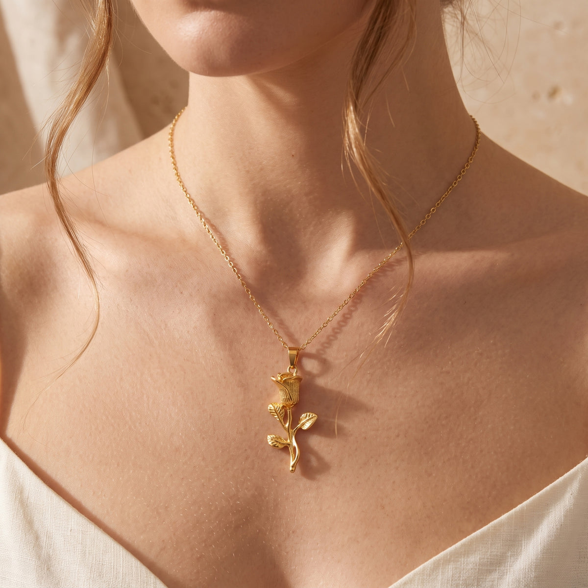 Model wearing the gold-tone rose pendant necklace, showcasing its length and fit against the neck.