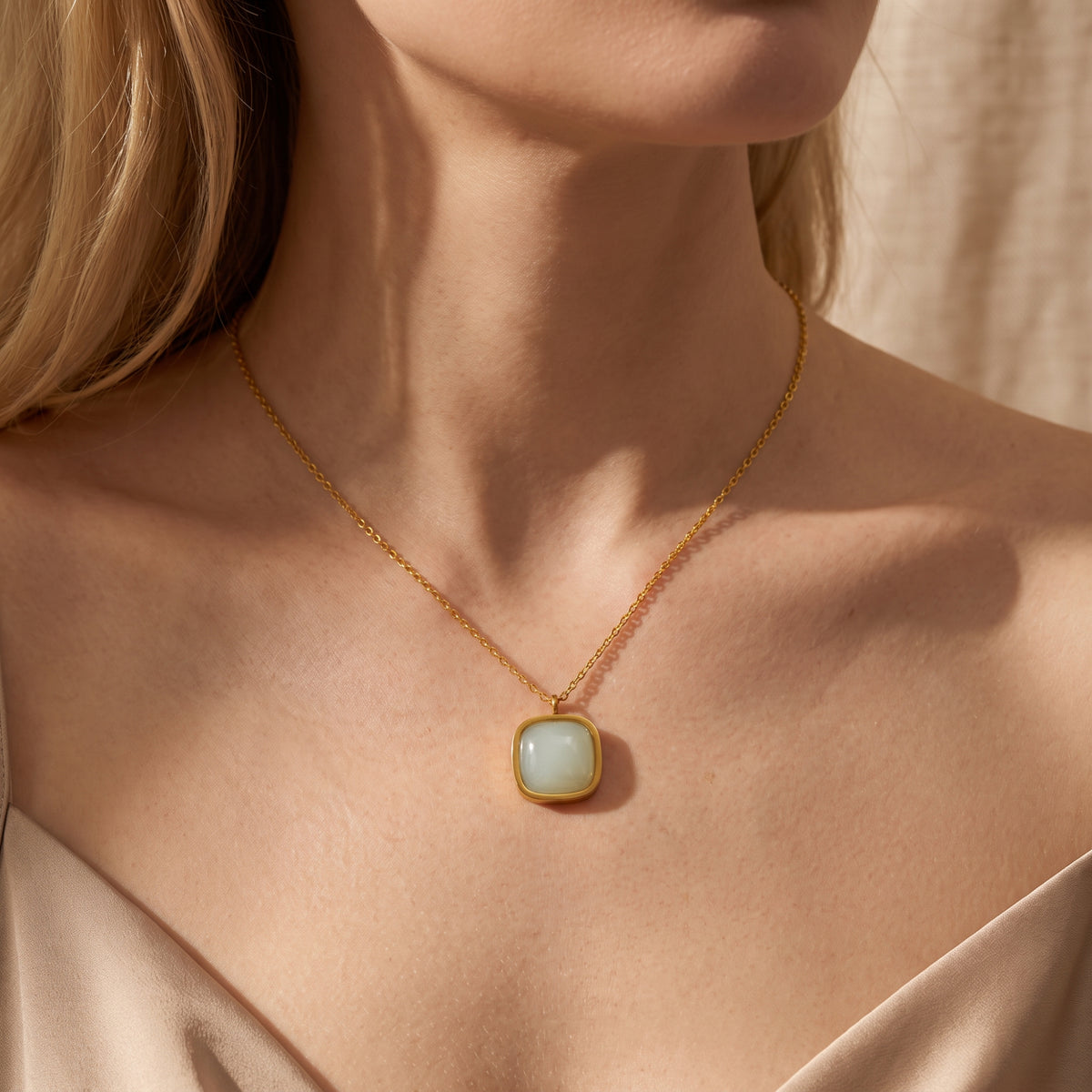 Frontal close-up of a model wearing the gold-tone cushion pendant necklace centered on her neckline.