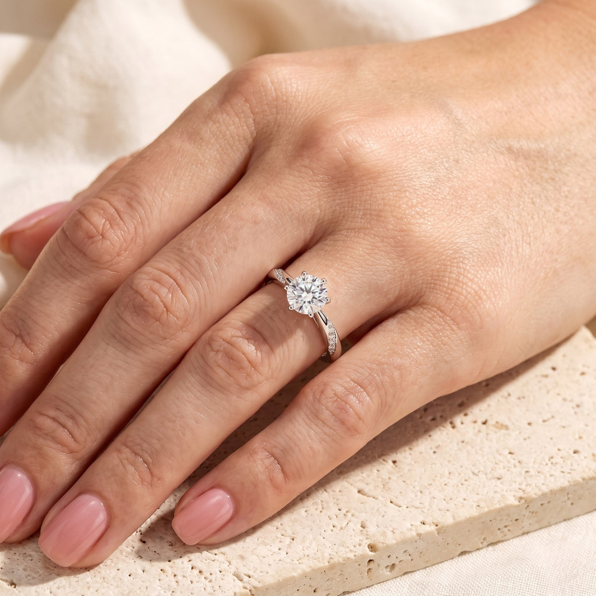Overhead view of a hand wearing a silver-tone round solitaire ring with a twisted pavé band.