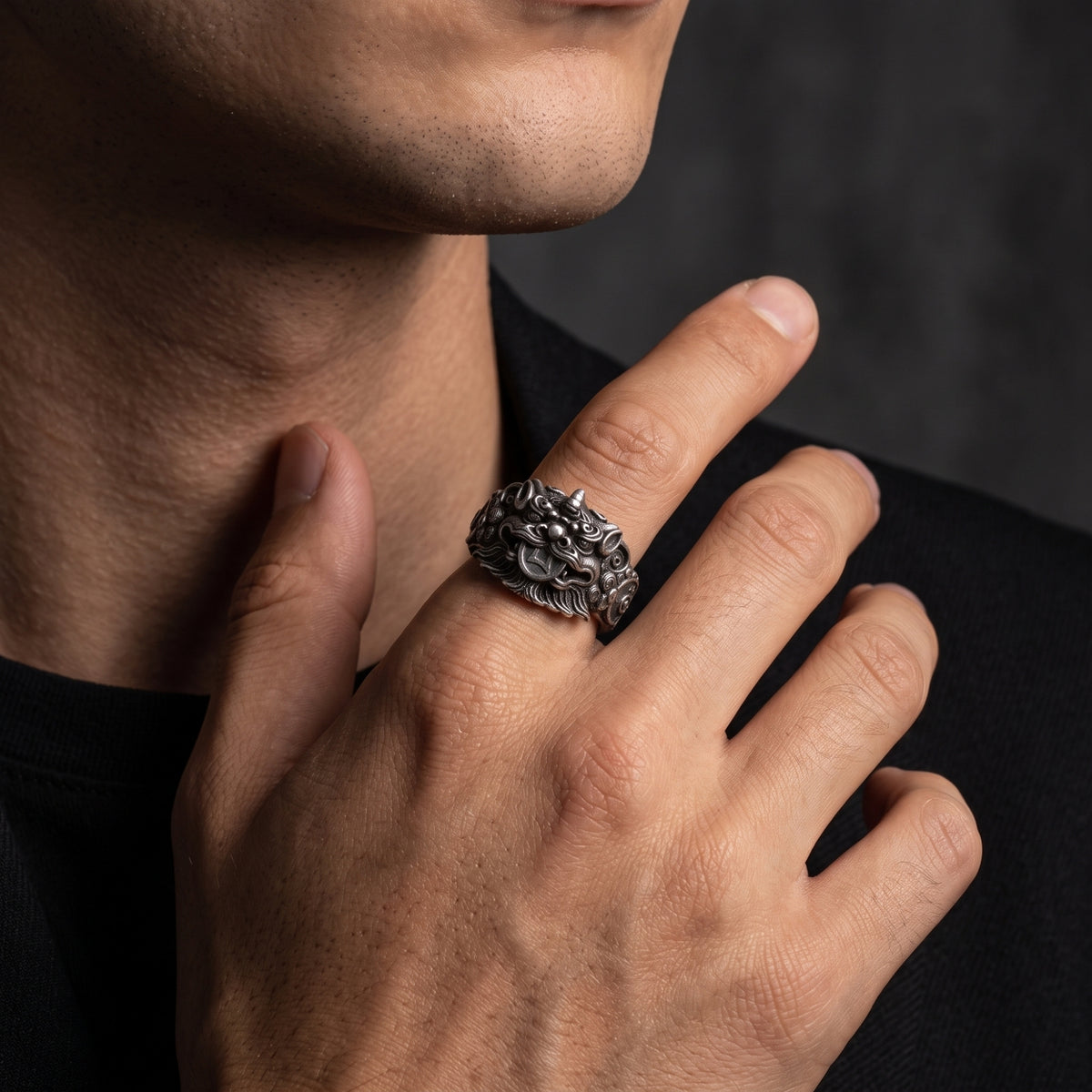 Close-up of a man wearing the silver Pixiu ring on his index finger near his chest.