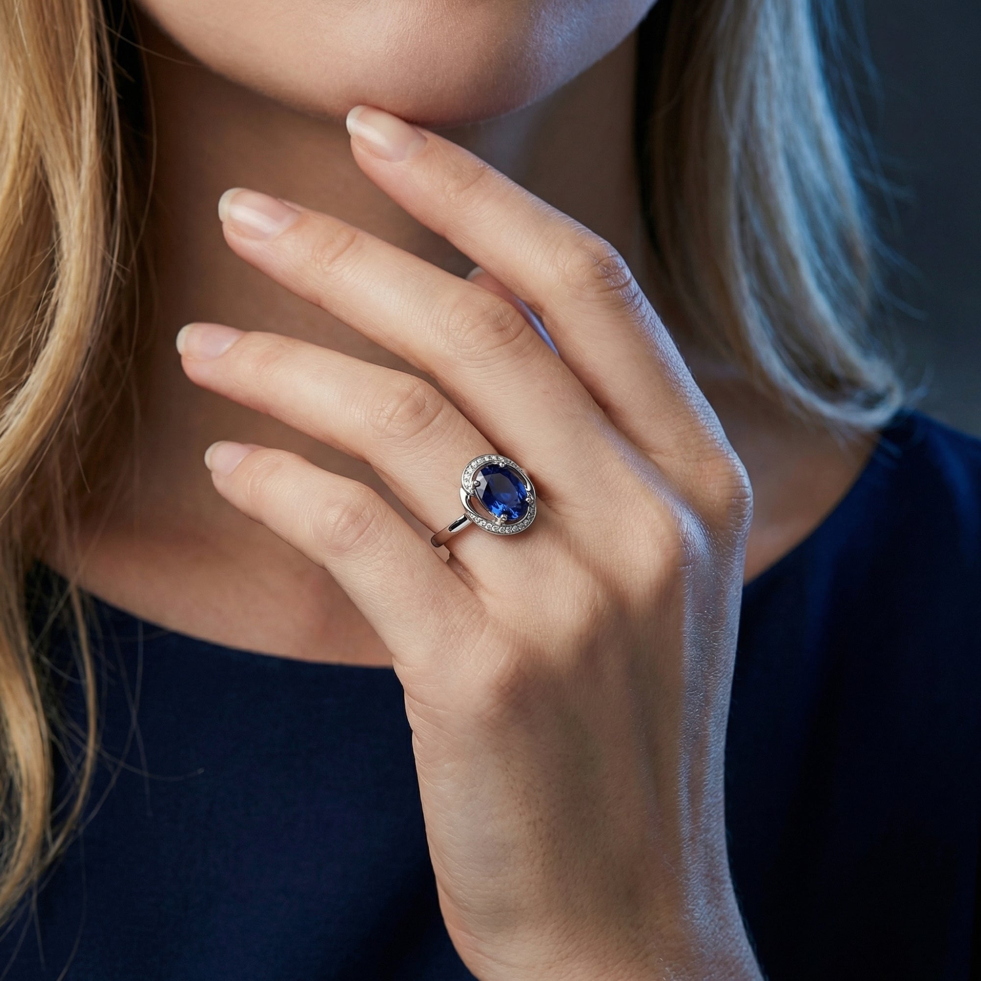 Model wearing the 18K white gold oval tanzanite ring with a diamond halo, showcasing the gemstone's deep blue color.