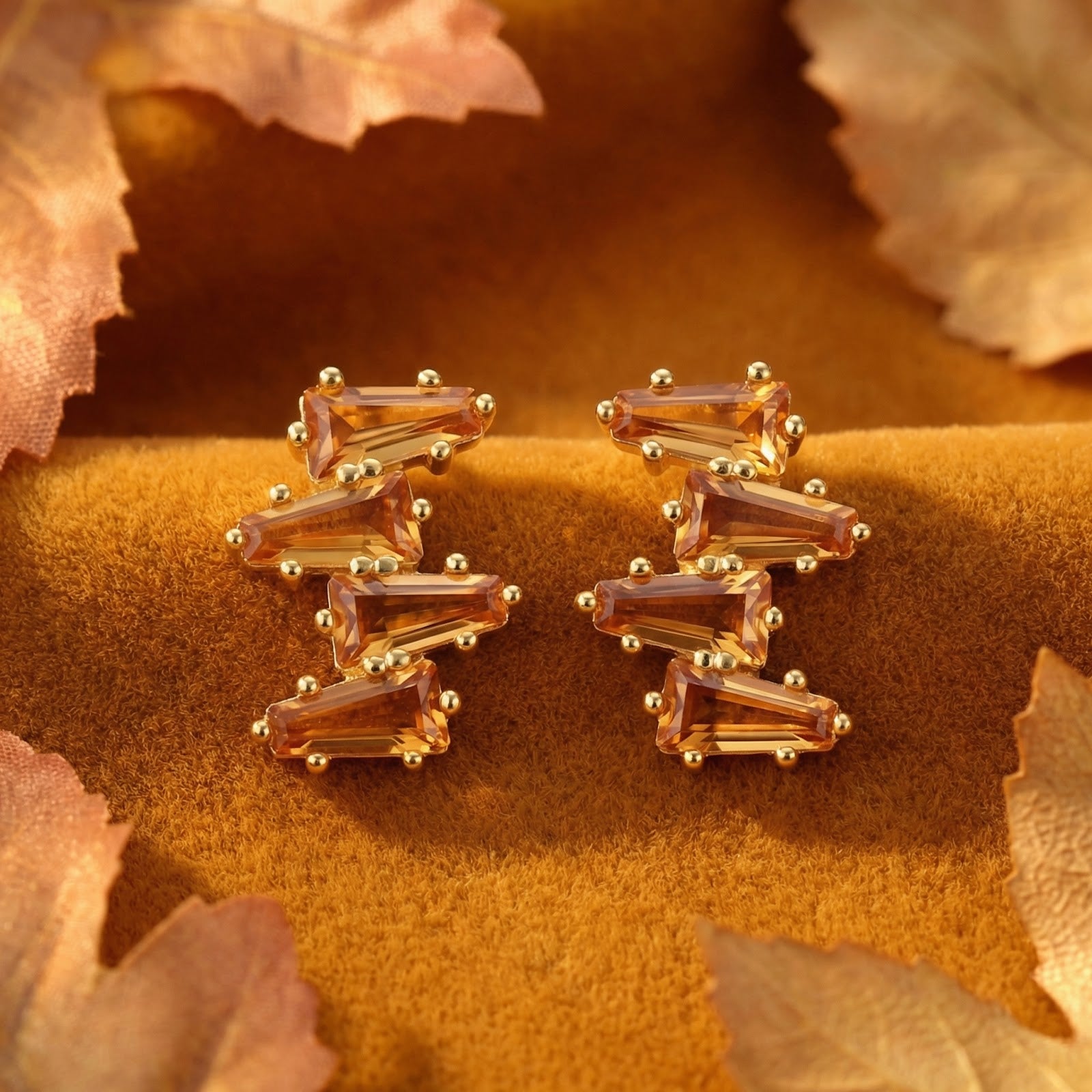 Close-up of Lyranelle cluster earrings in 18K gold vermeil featuring geometric-cut honeyed simulated topaz stones.