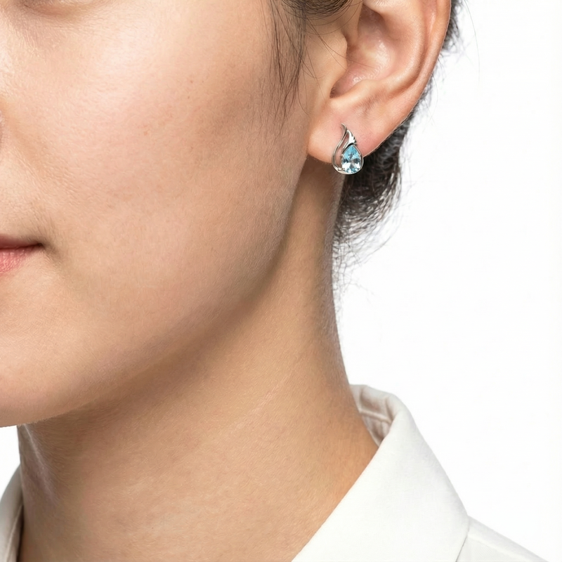 Side profile of a woman wearing a sterling silver Nerina drop earring with a light blue simulated stone.