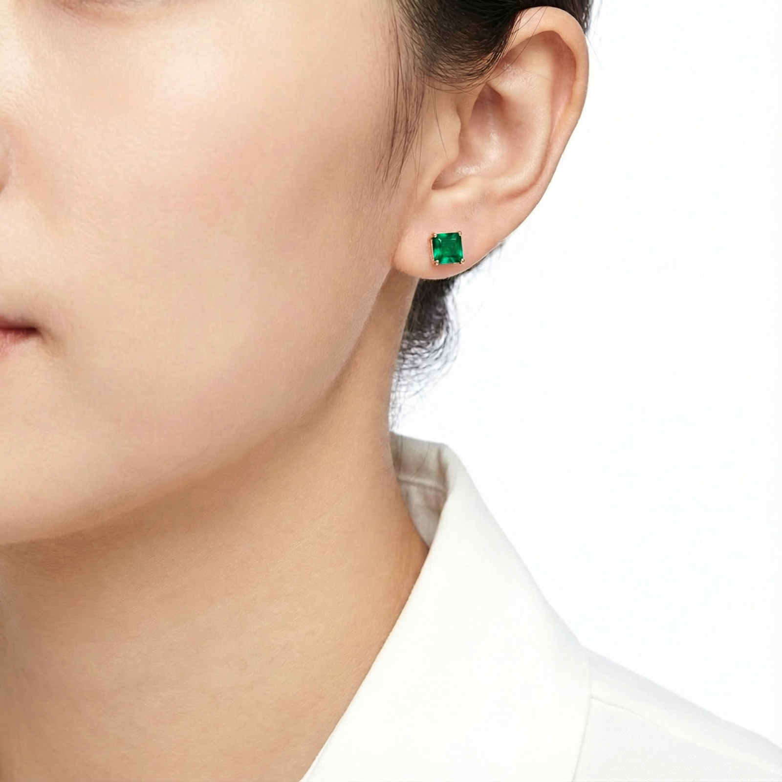 Square-cut simulated emerald stud earring in 18K rose gold vermeil worn on a model's ear.