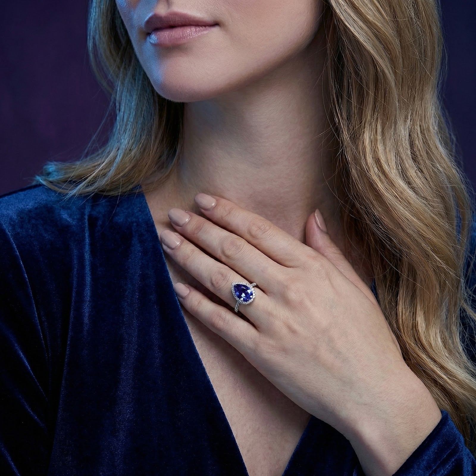 Pear cut simulated tanzanite sterling silver ring worn on a model's hand against a blue velvet dress.