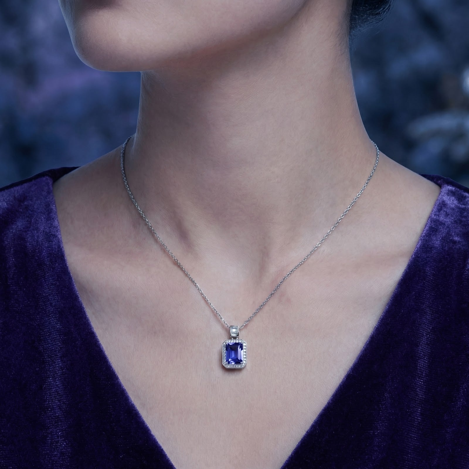 Woman wearing the Myrenne emerald-cut simulated tanzanite necklace in sterling silver against a dark background.
