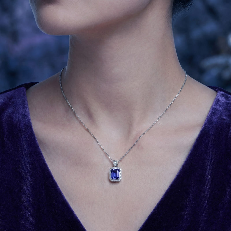 Woman wearing the Myrenne emerald-cut simulated tanzanite necklace in sterling silver against a dark background.