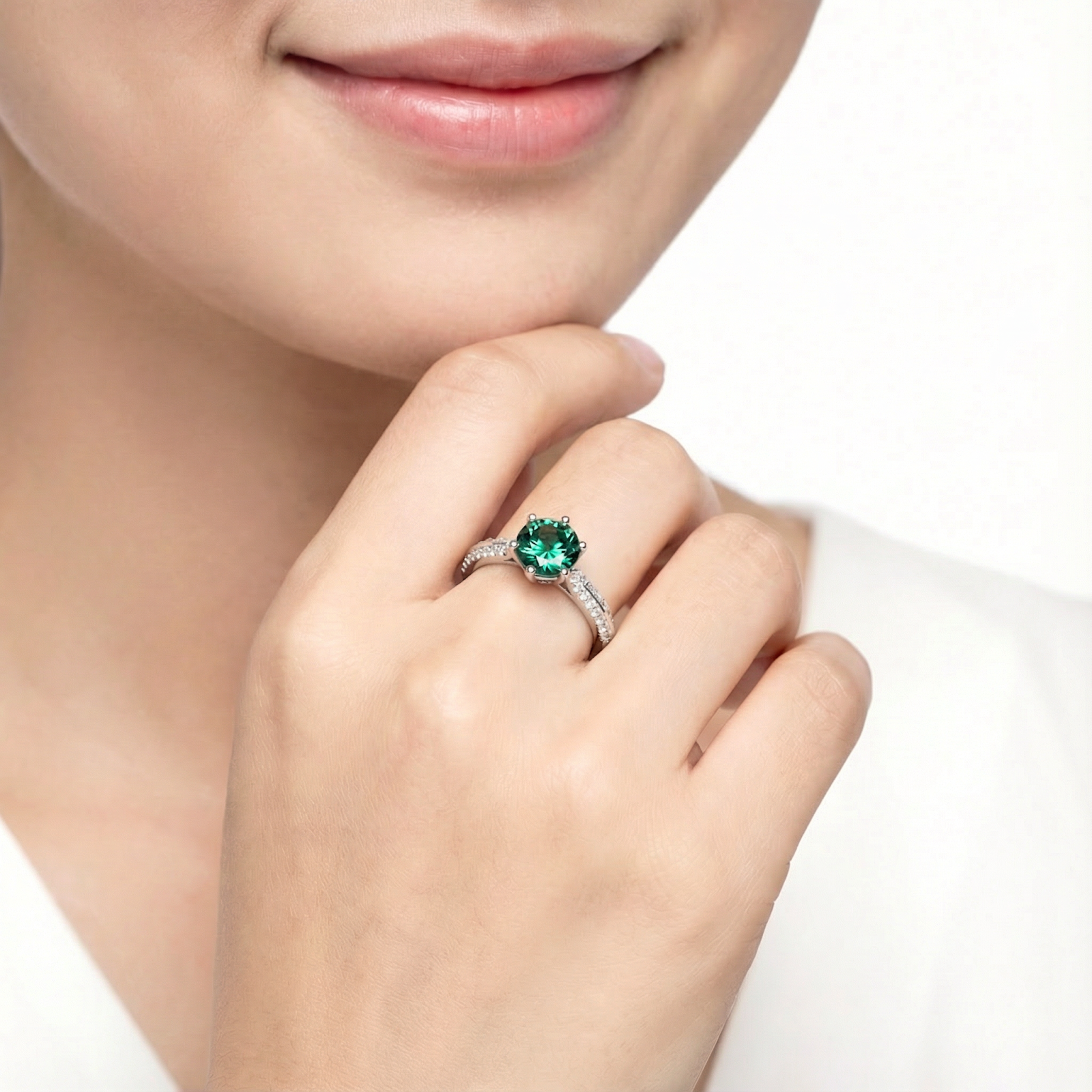 Model wearing the forest green round simulated emerald halo ring in sterling silver on her ring finger.