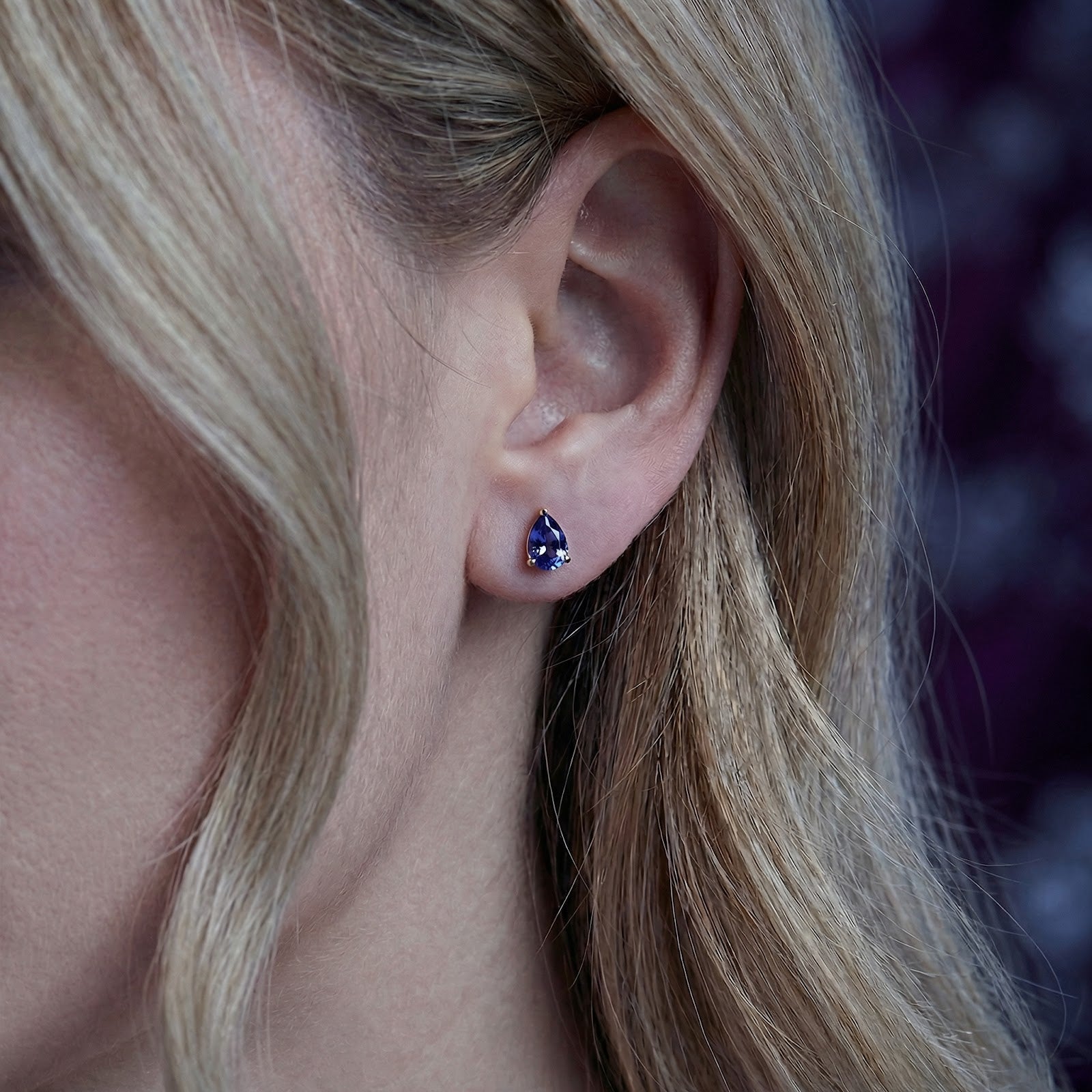 Side view of a model wearing the Mirellise pear-cut simulated tanzanite earring in 18K gold vermeil.