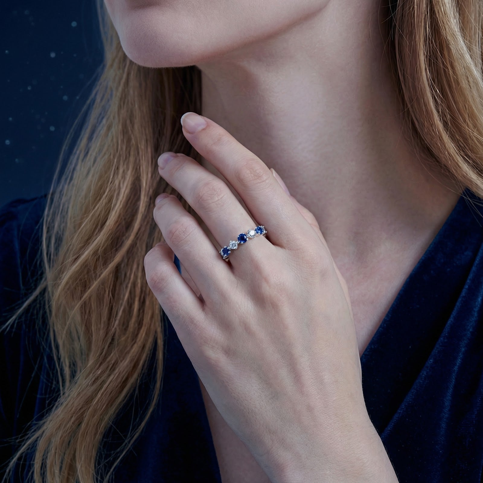 Thalissara sterling silver row ring with blue simulated sapphires worn on a woman's hand.