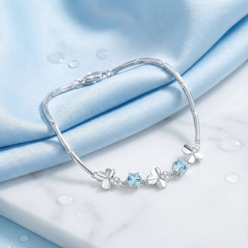 March birthstone station bracelet in S925 sterling silver with round light blue stones on blue silk.