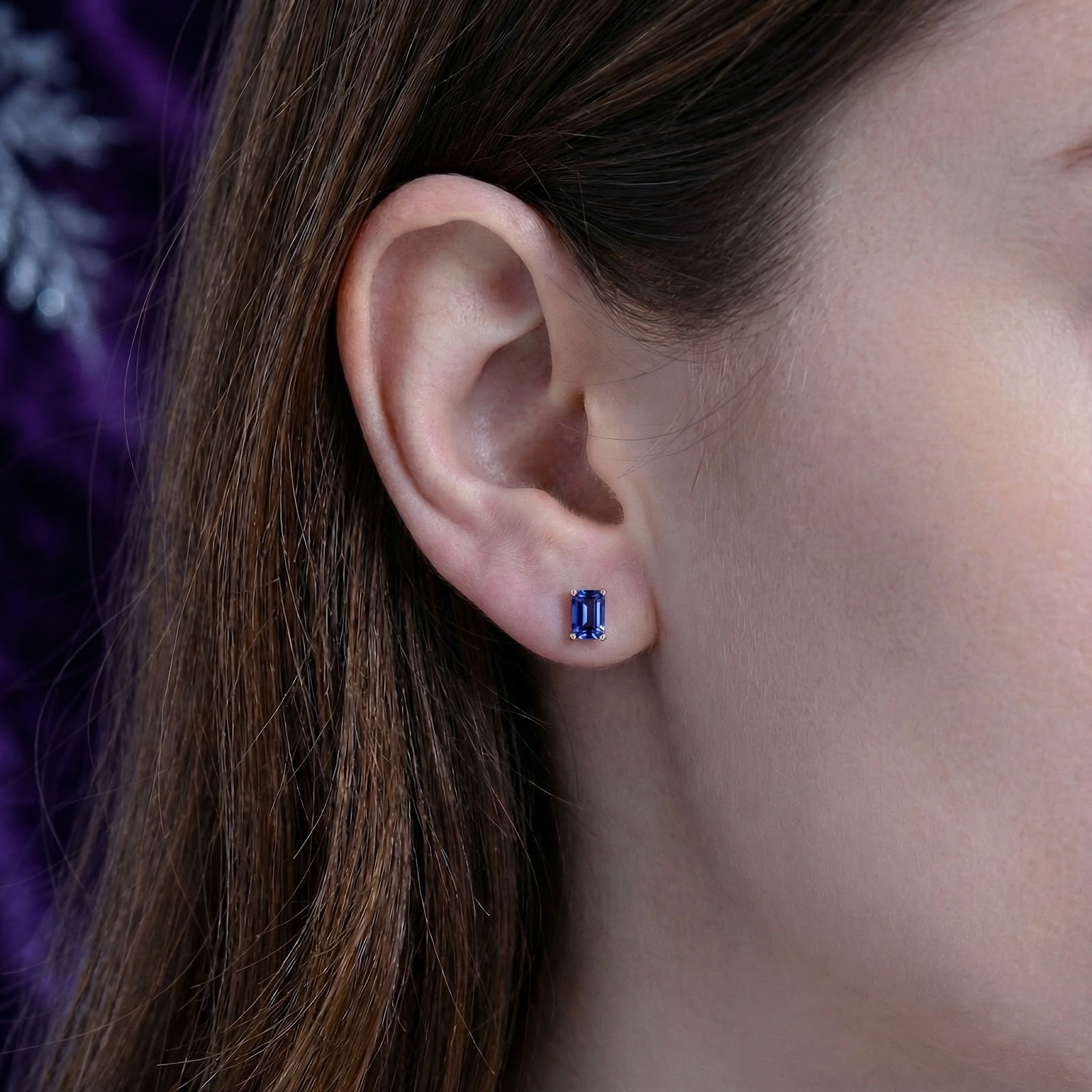 Model wearing a single emerald-cut simulated tanzanite stud earring in 18K gold vermeil on the earlobe.