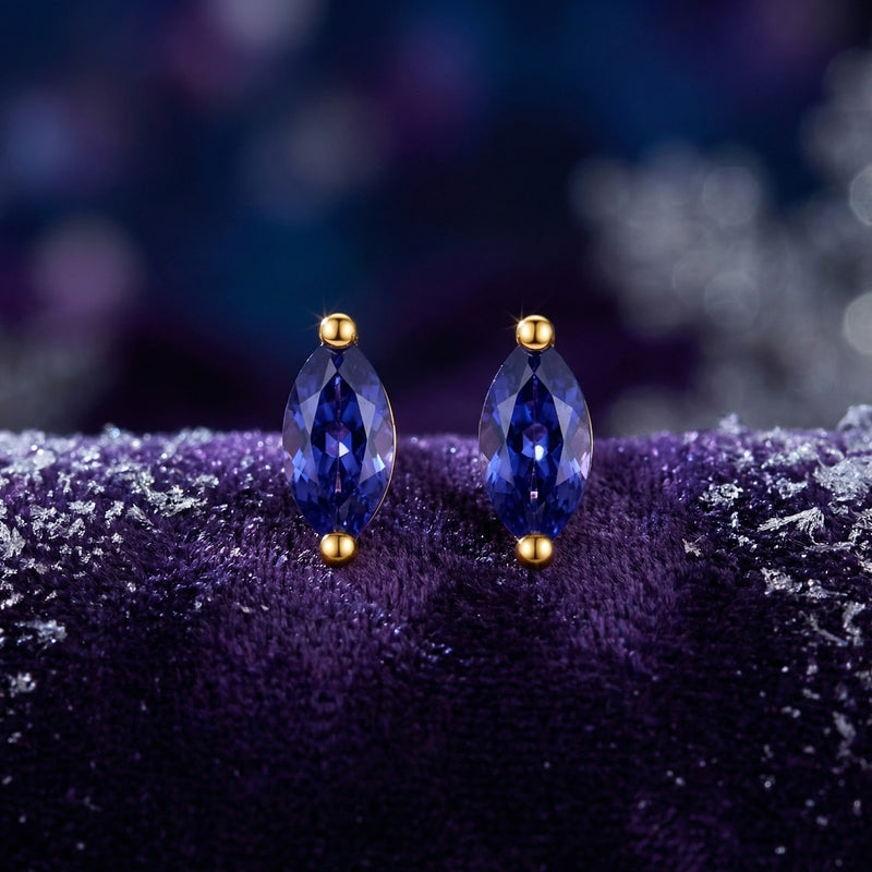 Close-up of marquise-cut simulated tanzanite earrings in 18K gold vermeil on a purple velvet background.