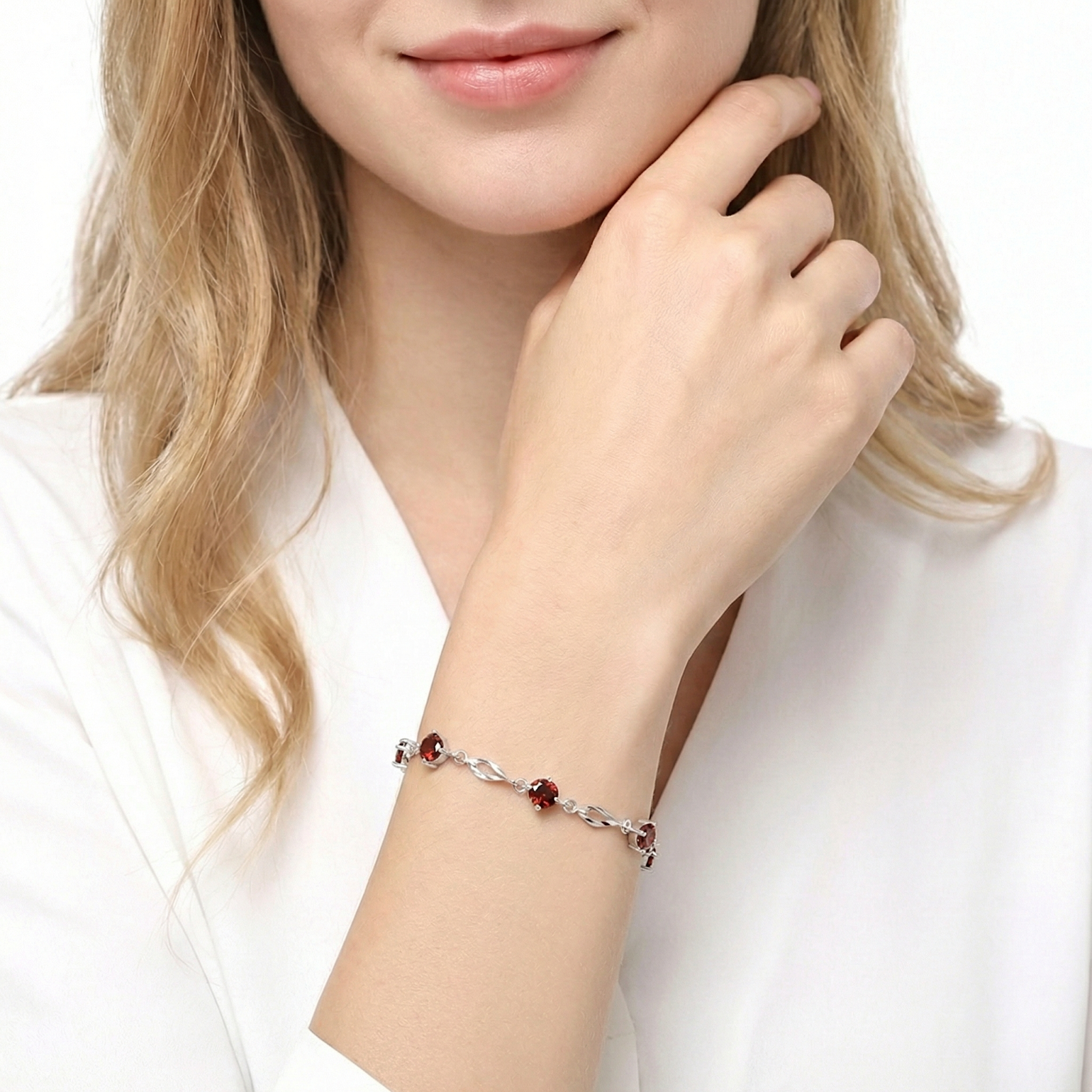 The Eliora sterling silver station bracelet with round red garnets worn on a woman's wrist.