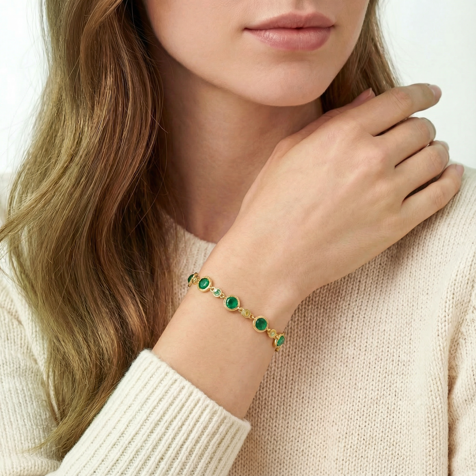 Woman wearing the Elianara gold vermeil station bracelet with green simulated emeralds on her wrist.