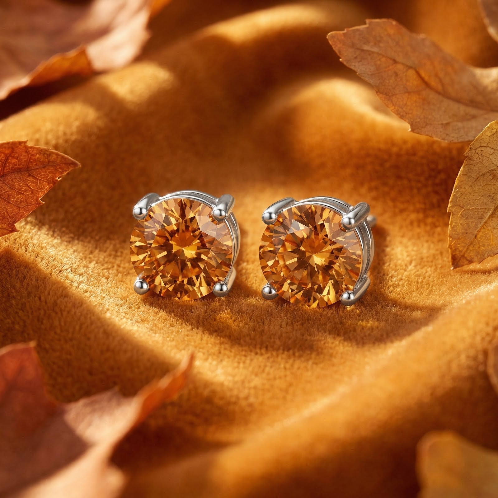 Round cut simulated topaz stud earrings in silver basket settings on golden velvet with autumn leaves.
