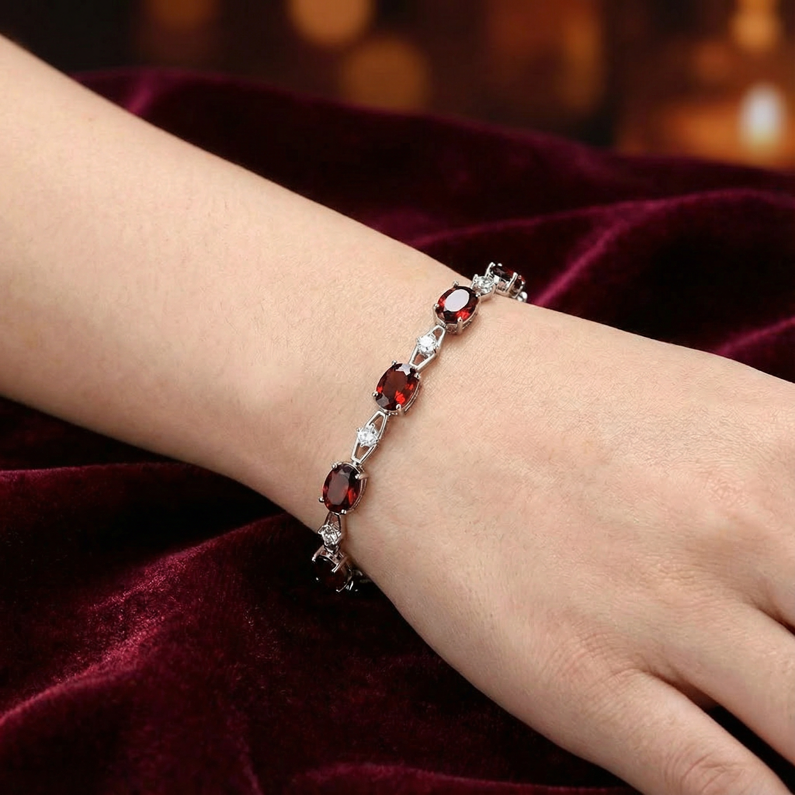 Oval cut red simulated garnet helix bracelet in S925 sterling silver shown on a woman's wrist.