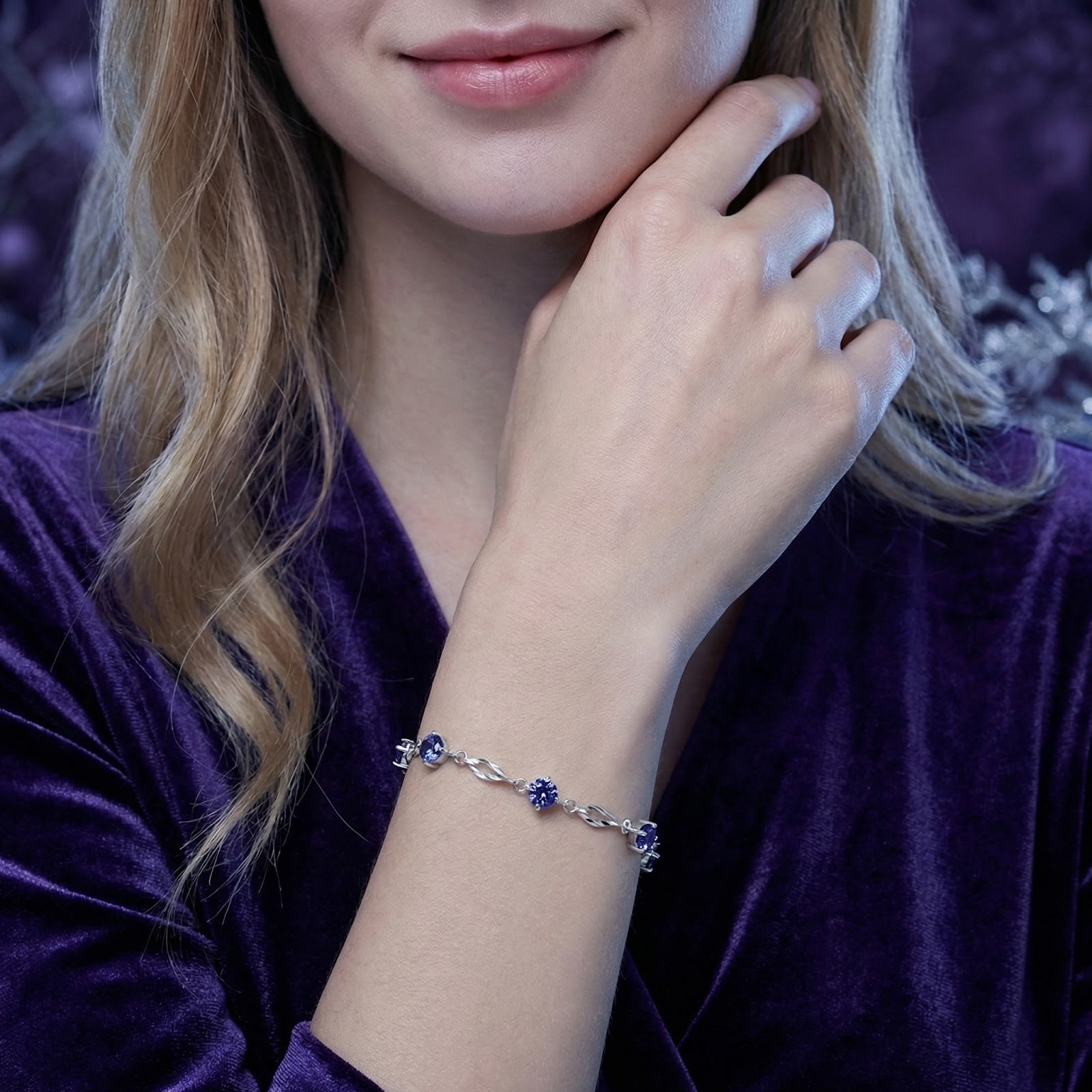 Sterling silver Nerisette station bracelet with blue simulated tanzanite stones worn on a woman's wrist.