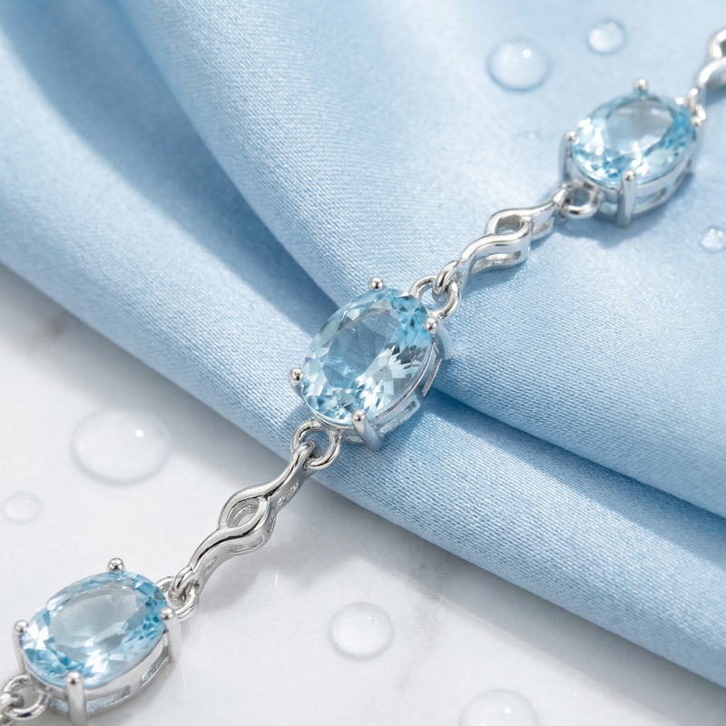 Close-up of oval cut light blue simulated aquamarine stones in a sterling silver station bracelet setting.