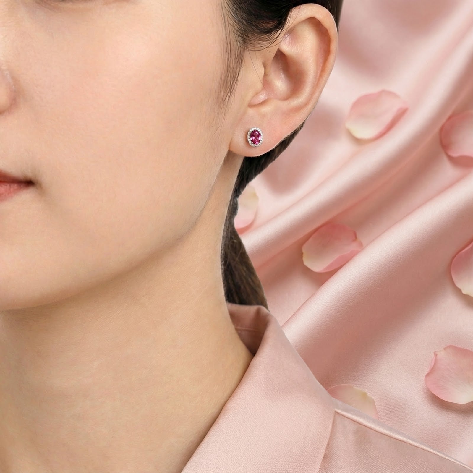 Model wearing a sterling silver halo stud earring with an oval-cut simulated pink tourmaline stone.