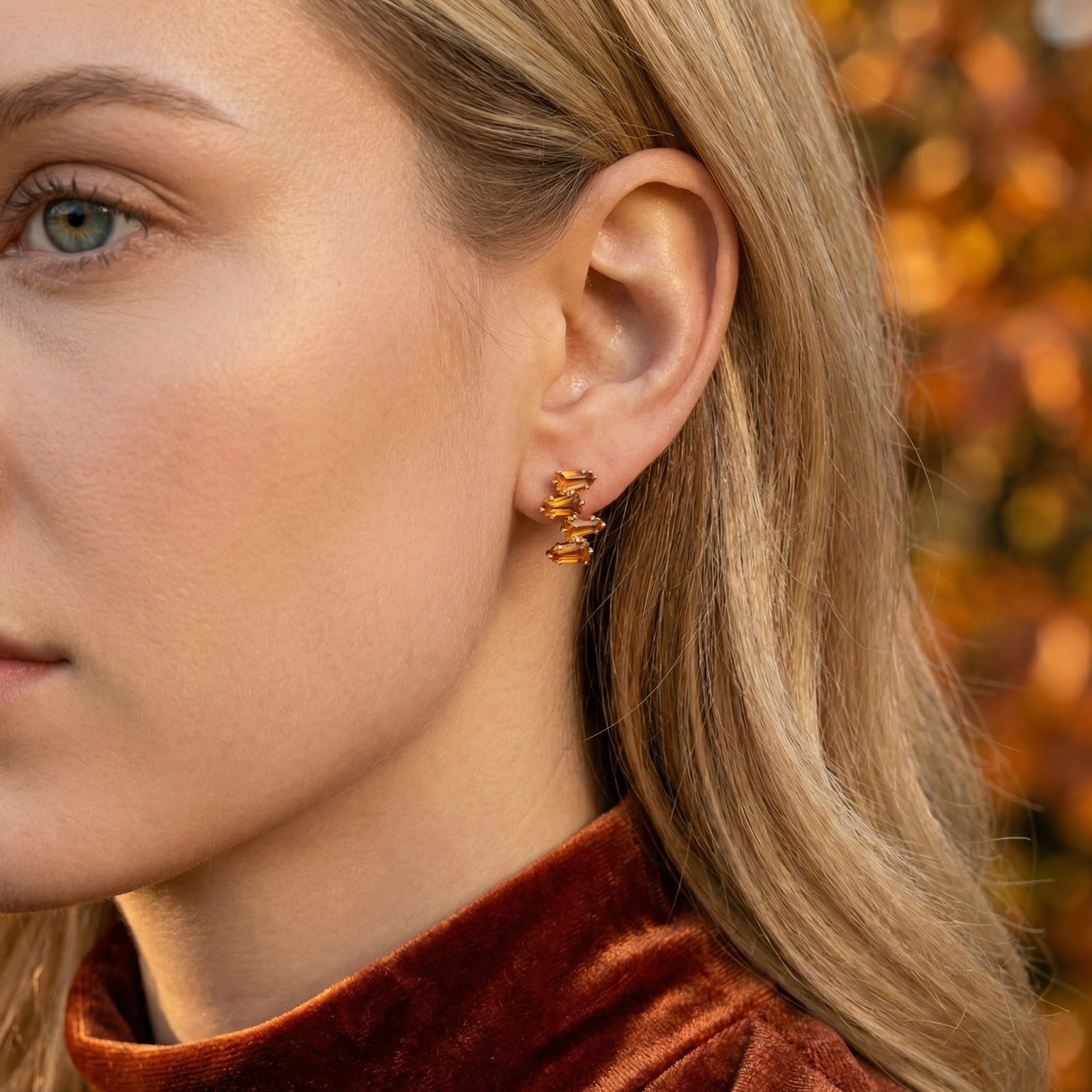Front view of a model wearing the Lyranelle 18K gold vermeil cluster earring with geometric simulated topaz stones.