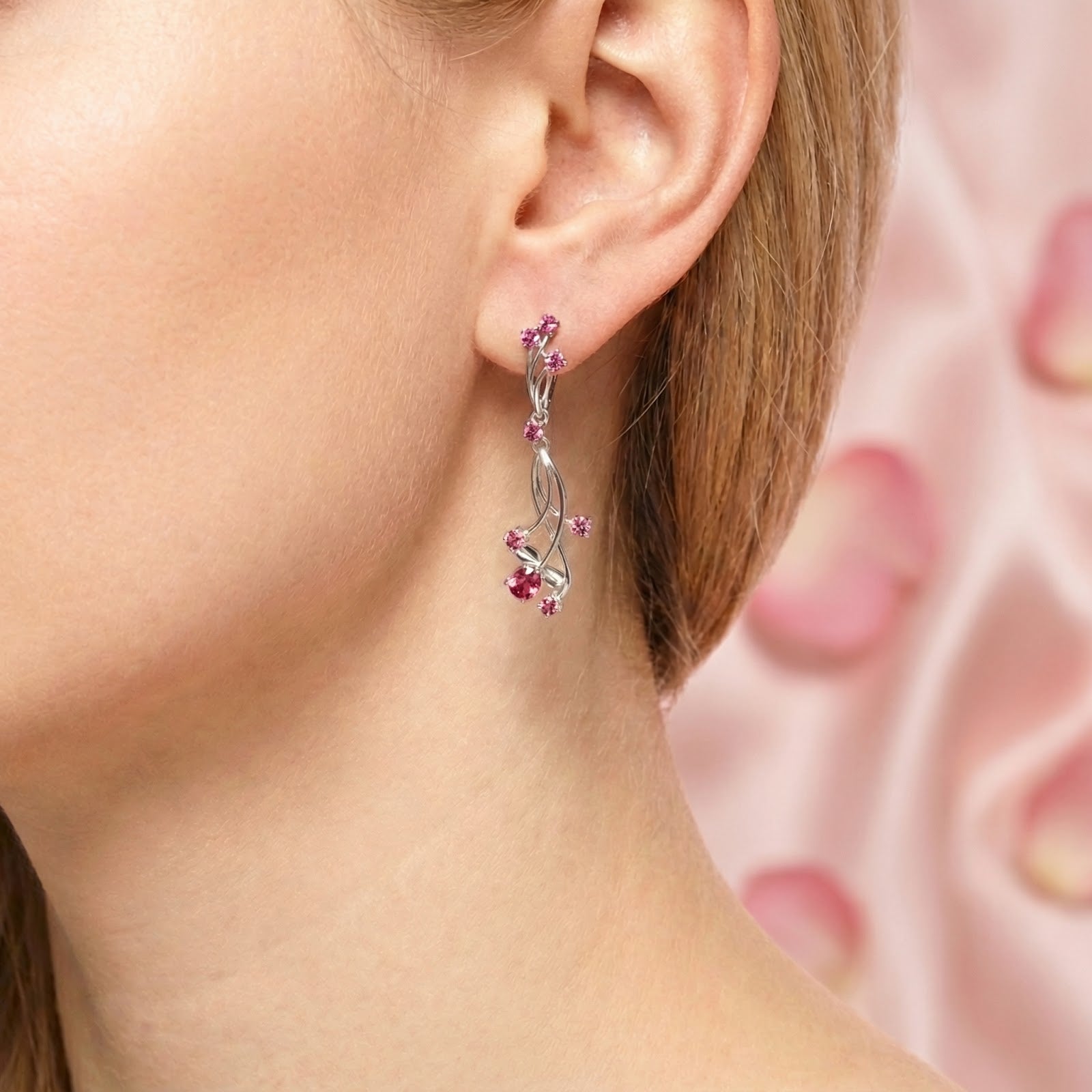 Close-up of a sterling silver vine drop earring with pink tourmaline stones worn on a model's ear.