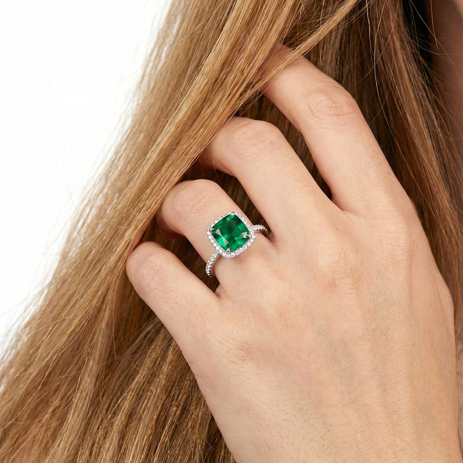 Close-up of a cushion-cut simulated emerald sterling silver ring worn on a hand, showing the pavé band detail.