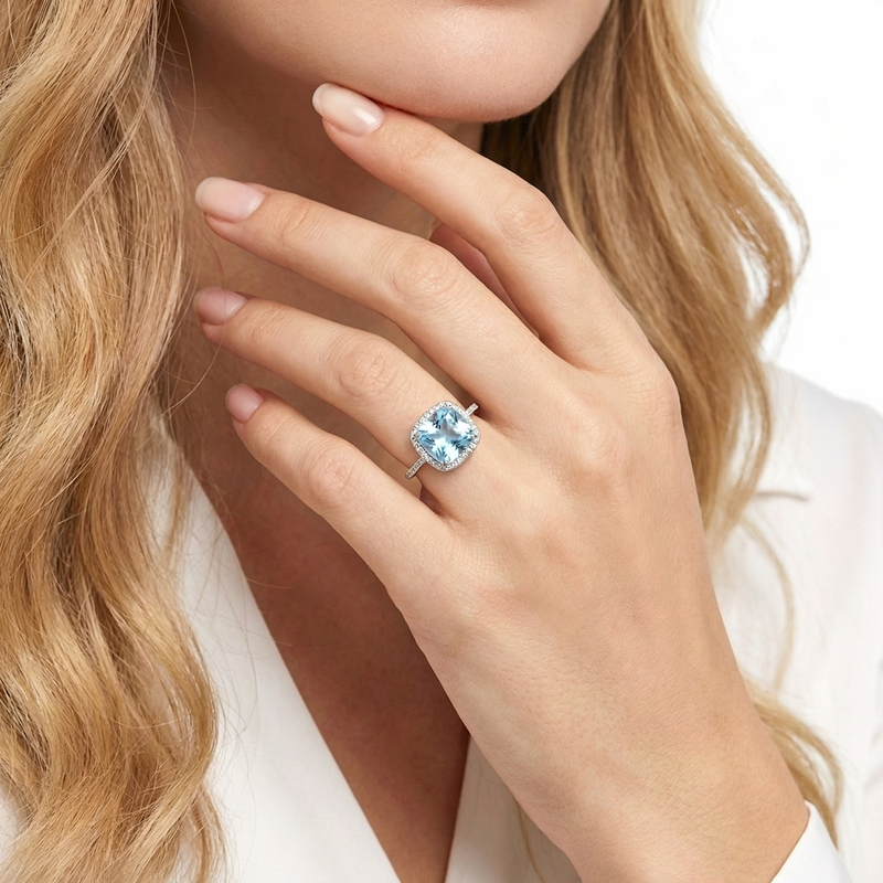 Woman wearing the cushion-cut simulated aquamarine halo ring in sterling silver on her finger.