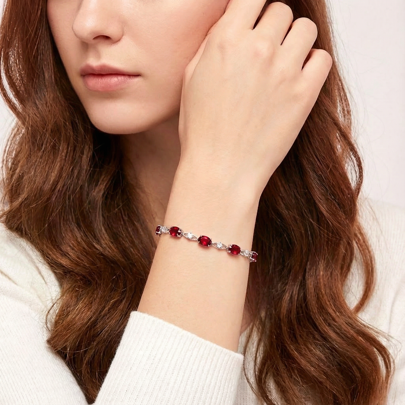Woman wearing the sterling silver Helixa station bracelet with red simulated rubies on her wrist.