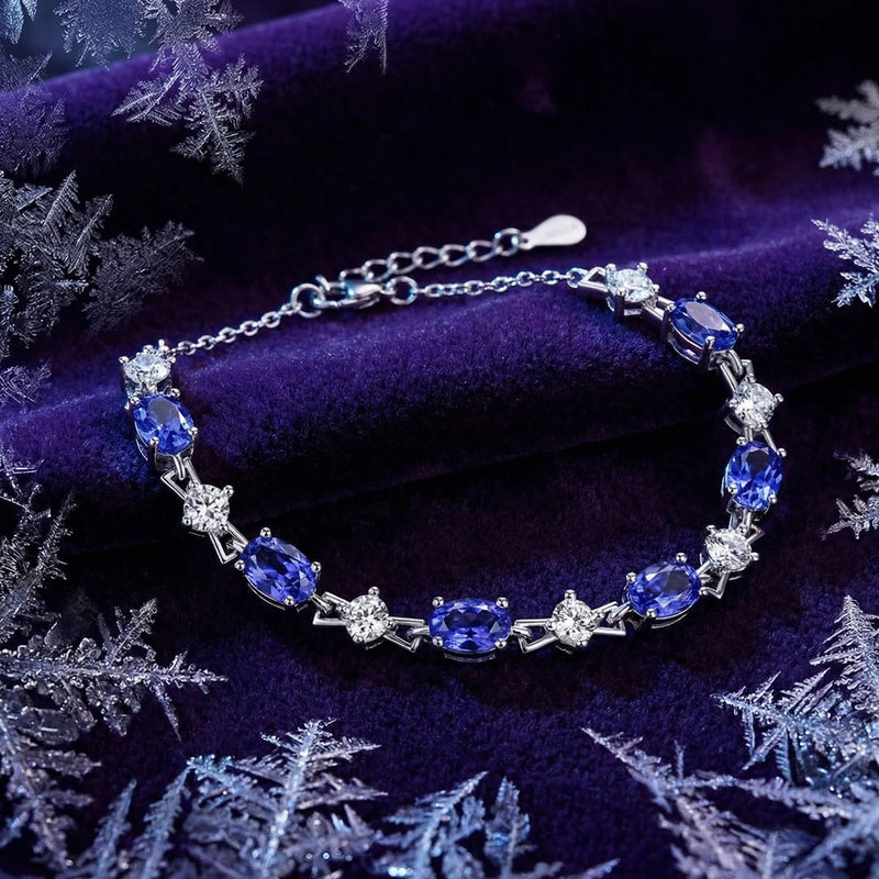 Top view of the sterling silver Zenelle station bracelet with oval-cut blue simulated tanzanite on purple velvet.