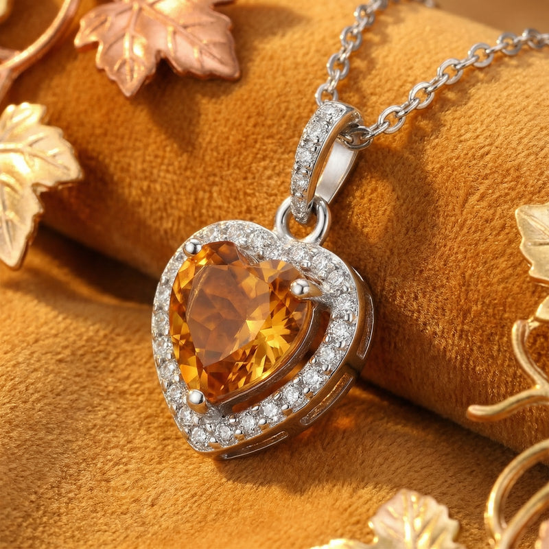 Close-up of a heart-cut simulated topaz pendant in a silver halo setting resting on gold velvet.